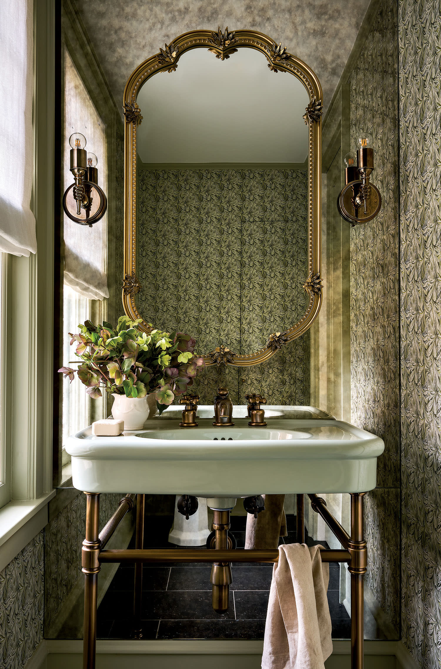 Elegant bathroom with a vintage, gold-framed mirror above a pale green sink. 