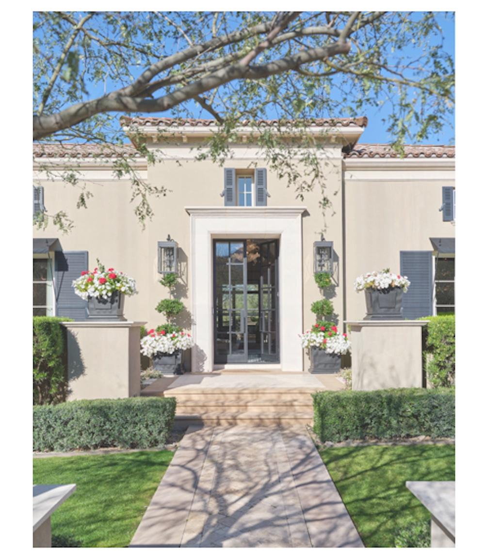 Welcoming front entrance with manicured landscape and flower boxes on each side of double doors.