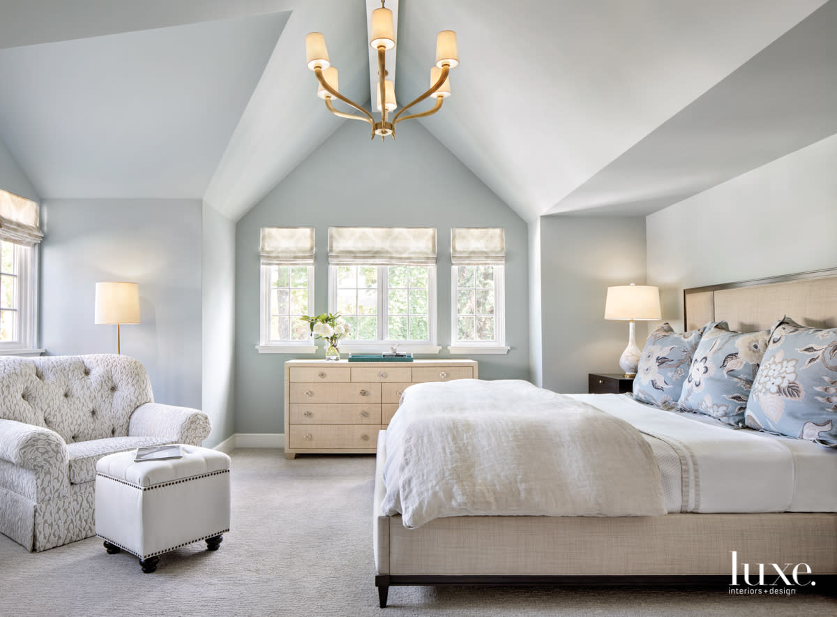 Master bedroom with high ceiling, light blue walls, and large comfy bed.