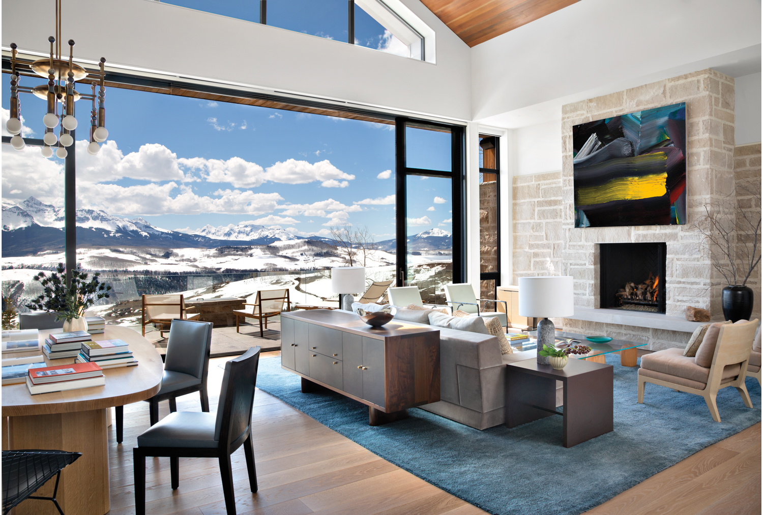 contemporary living room with open sliders to mountainous landscape, with fireplace, couch and deck area