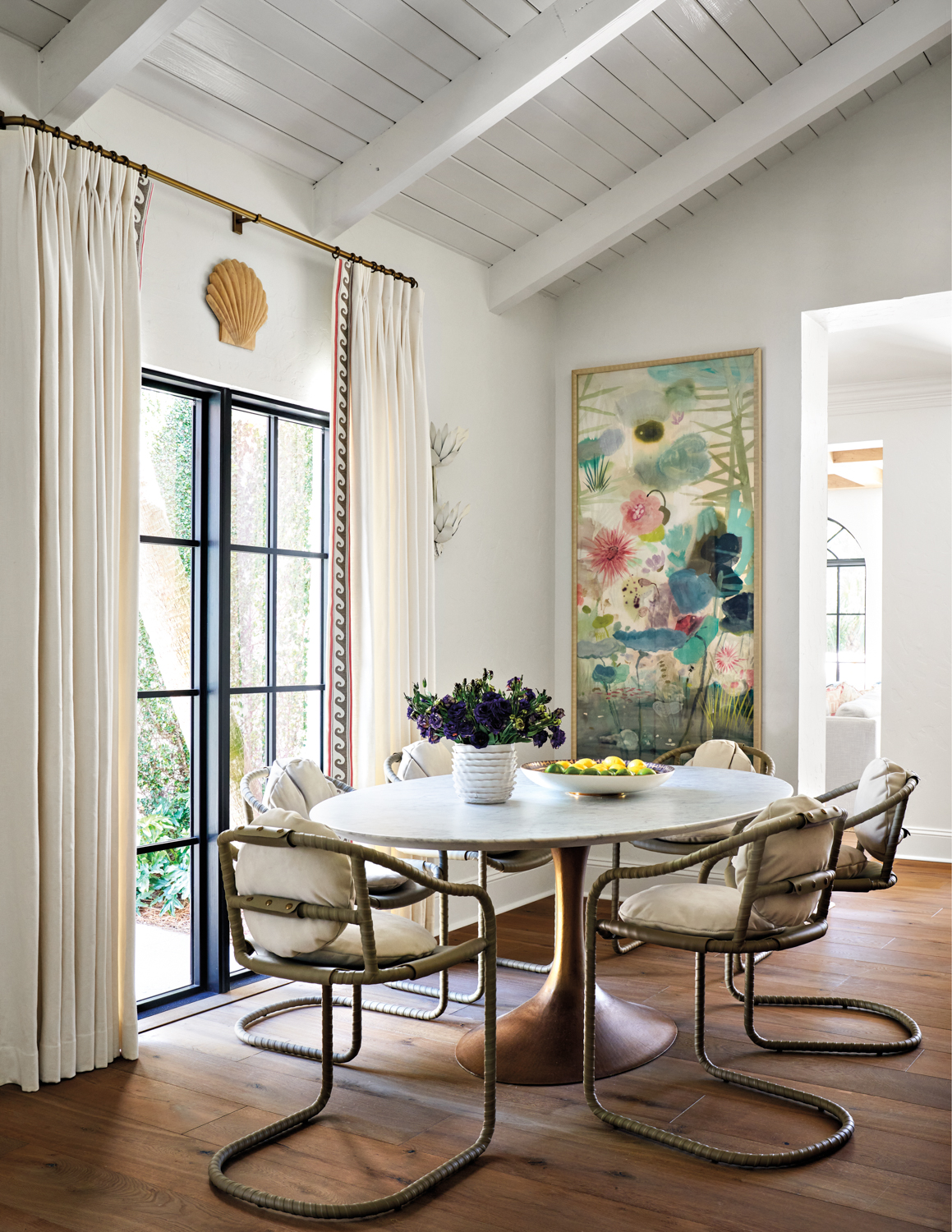 Breakfast area with modern furniture and colorful artwork next to French doors in home by Mary Beth Wagner