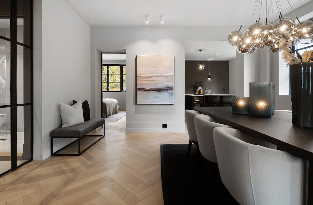 A contemporary dining room featuring European oak flooring and a spacious table beneath an elegant large chandelier, creating a sophisticated ambiance.