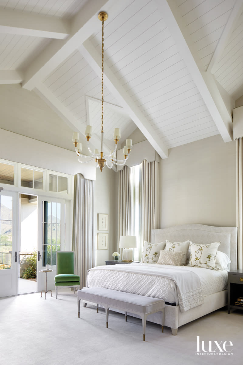 A white-and-cream bedroom with a green chair in the corner.