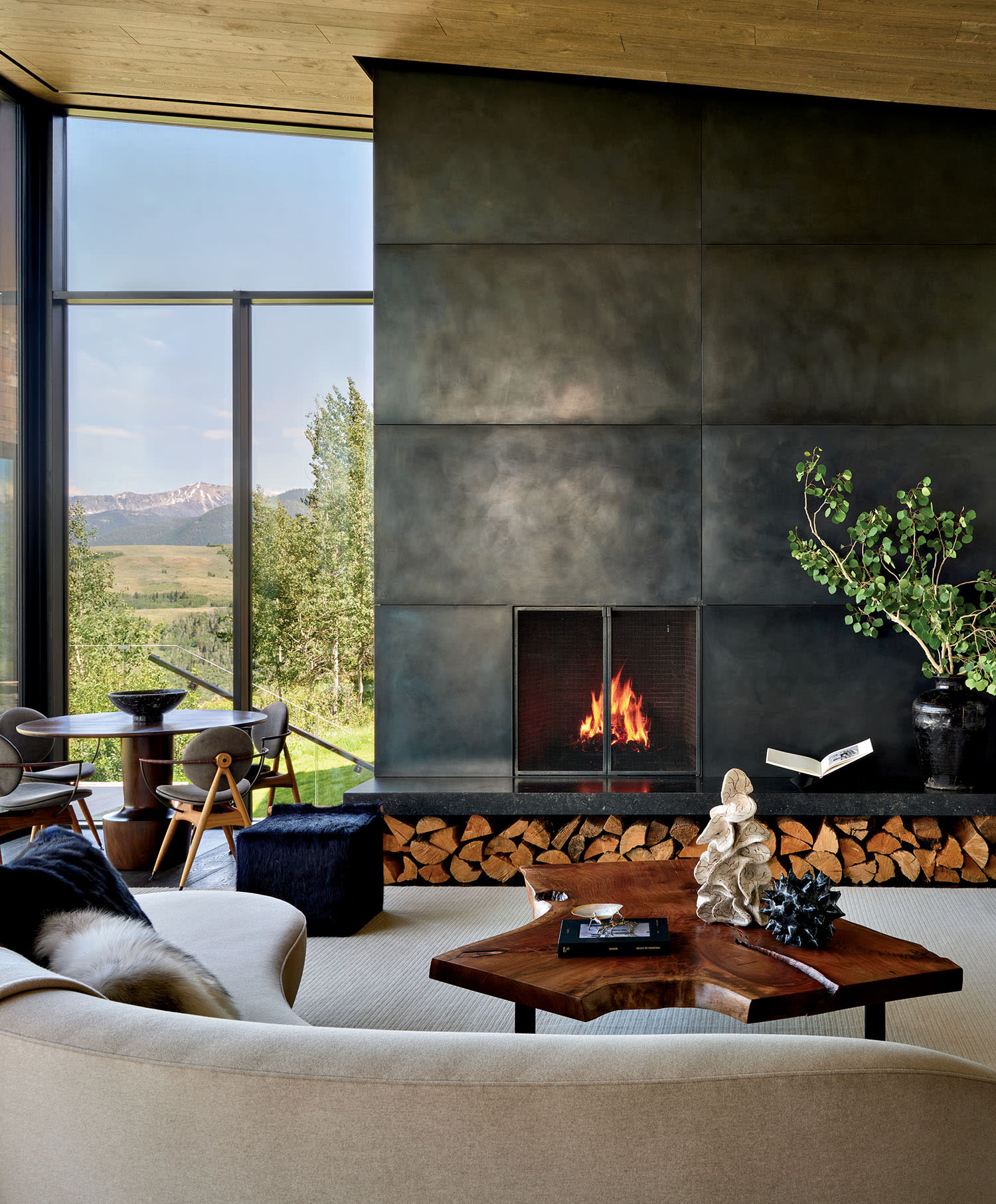 Stylish living room with large windows revealing mountain views. A modern fireplace, cozy seating, and elegant decor create a warm, inviting atmosphere.