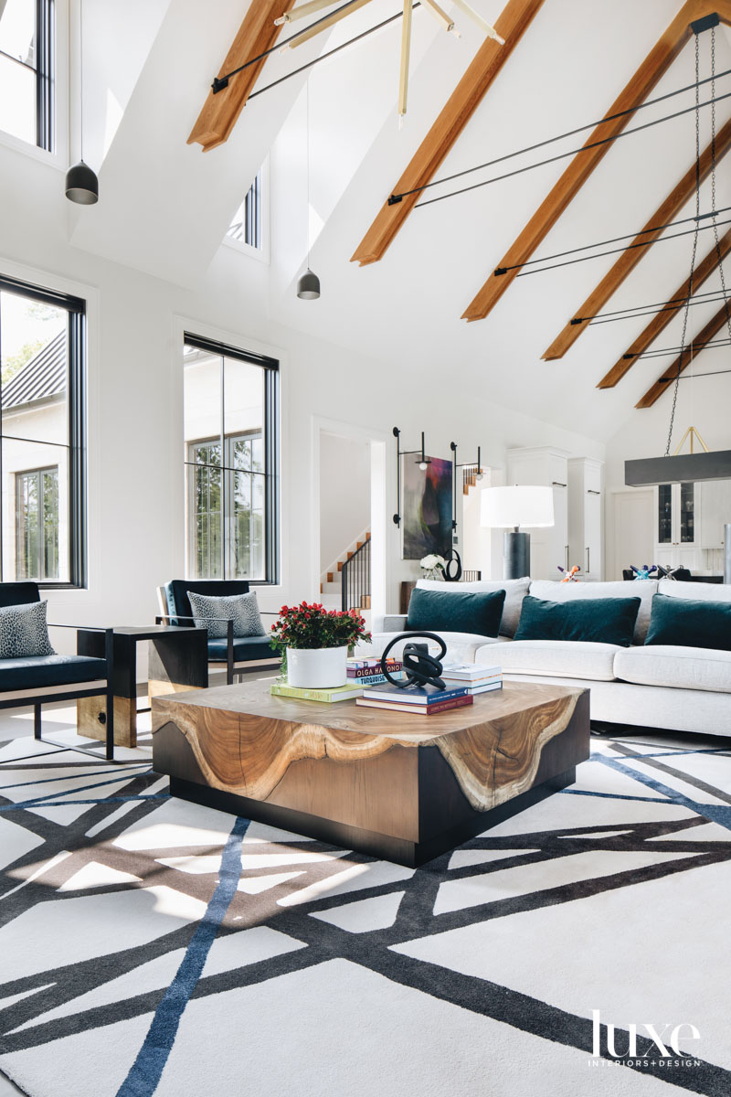 A living room with a graphic rug, white couch, two armchairs and a wood coffee table.