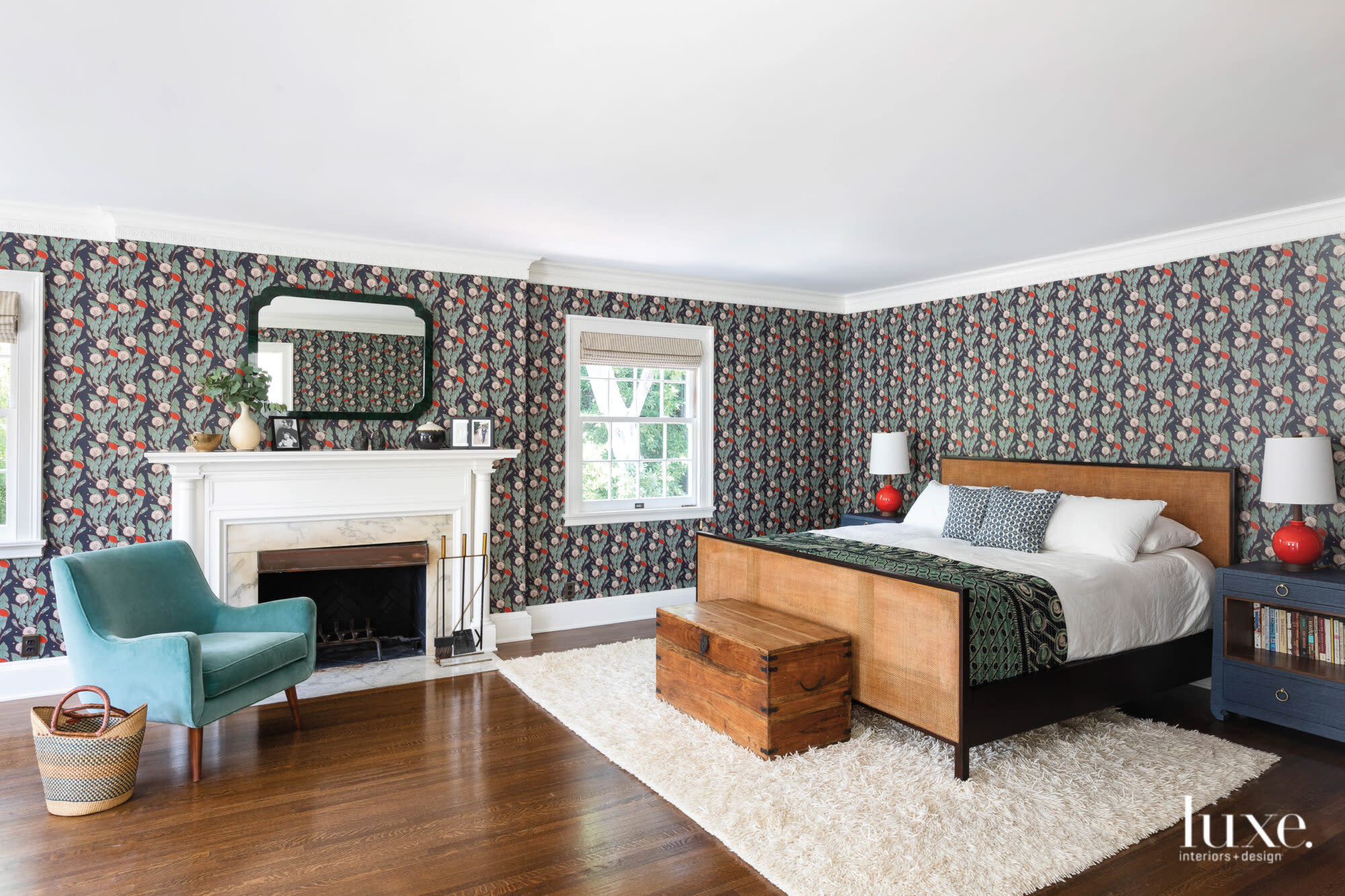 A bright bedroom with dark floral wallpaper and fireplace.