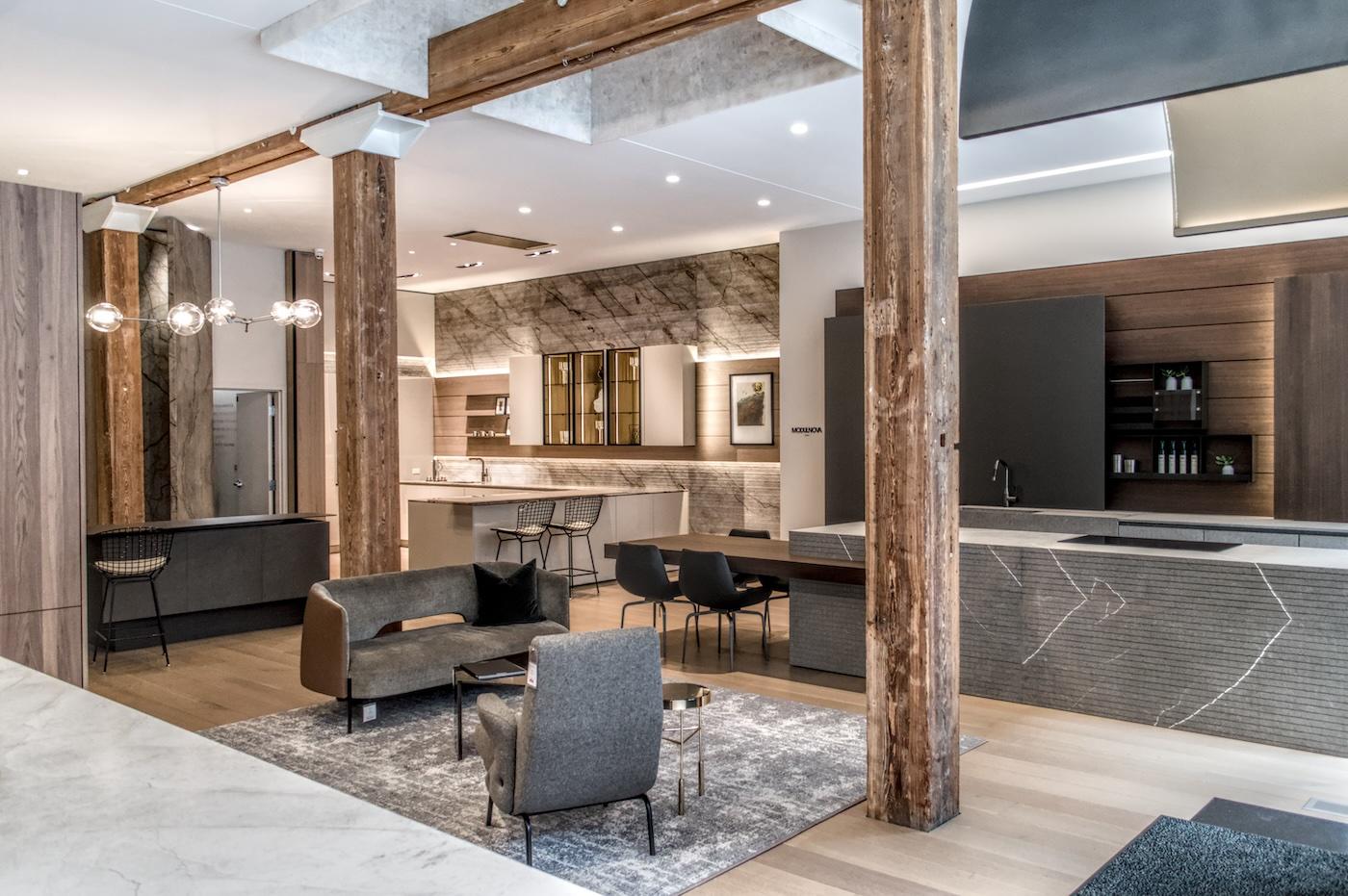 Modern, open-concept kitchen and living room with wood beams, sleek furniture, gray tones, and marble accents. Contemporary and inviting ambiance.