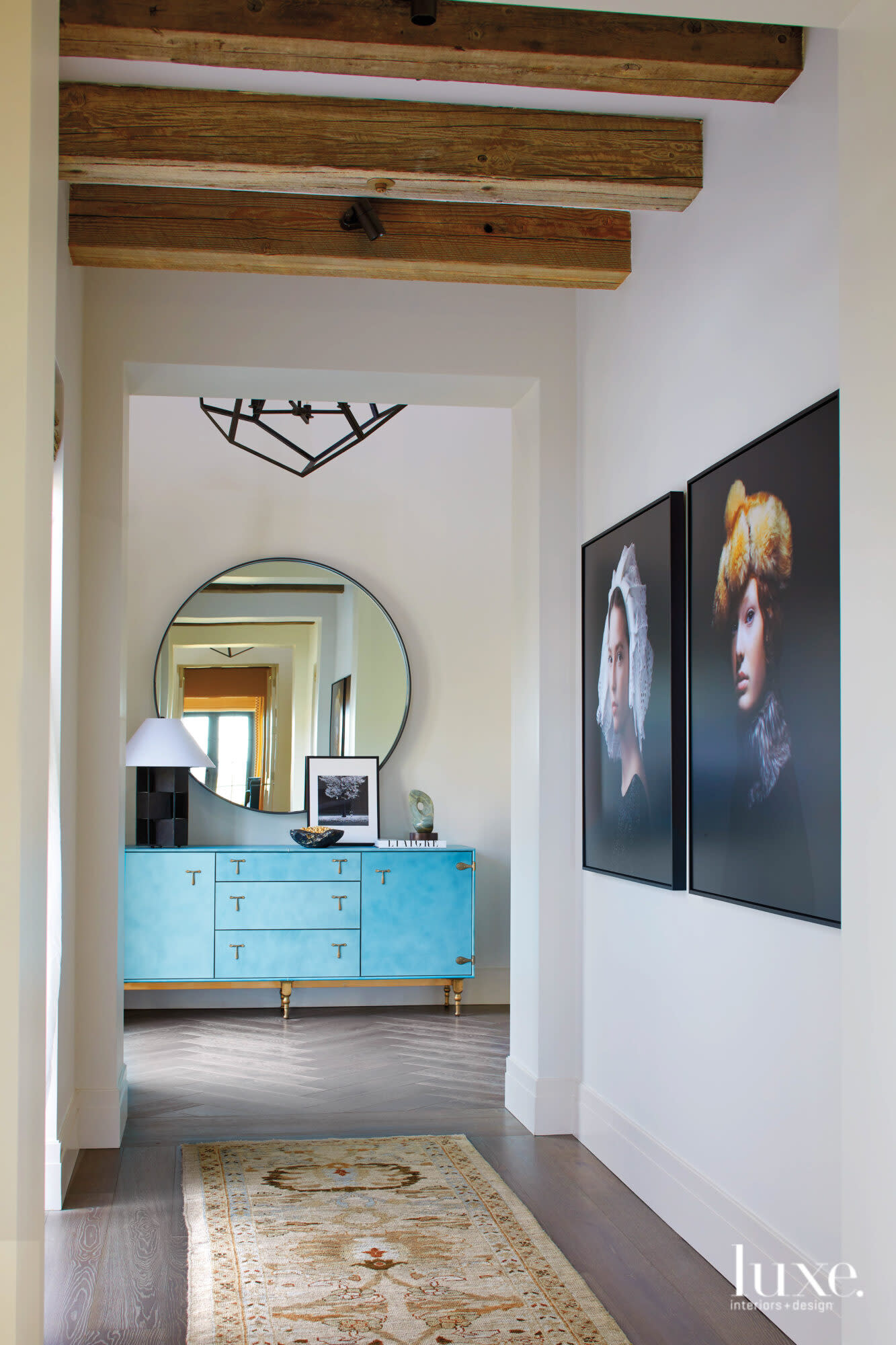 Two portraits and a blue dresser are what's first seen in the entryway