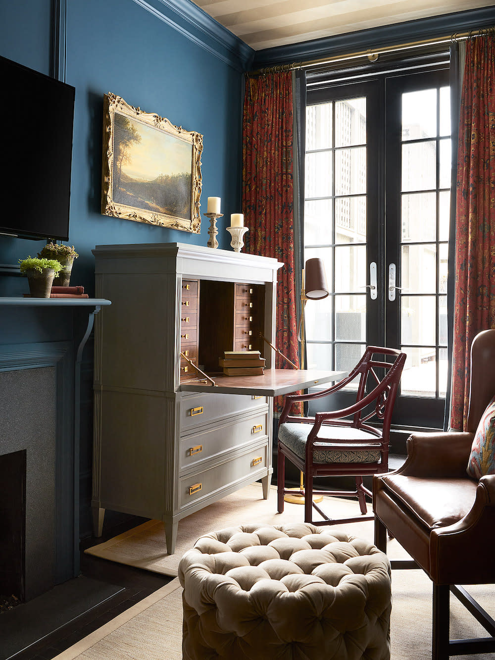 Double French doors allow alot of light into this den with blue walls and gold, stripped wall papered ceiling.