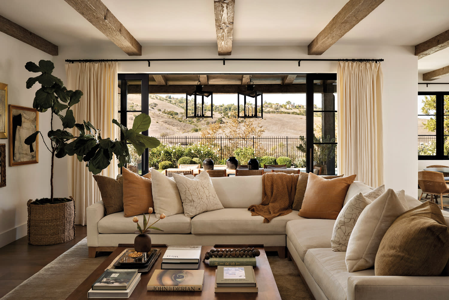 family room with exposed beams and a cream sectional topped with cream and tan pillows in home by Nicole Green