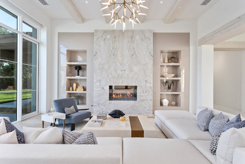 An inviting living room showcasing pristine white furniture alongside a classic fireplace, enhancing the space's warmth.