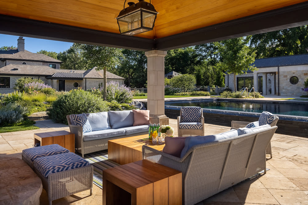 Covered outdoor seating area overlooking the pool and landscaped yard.