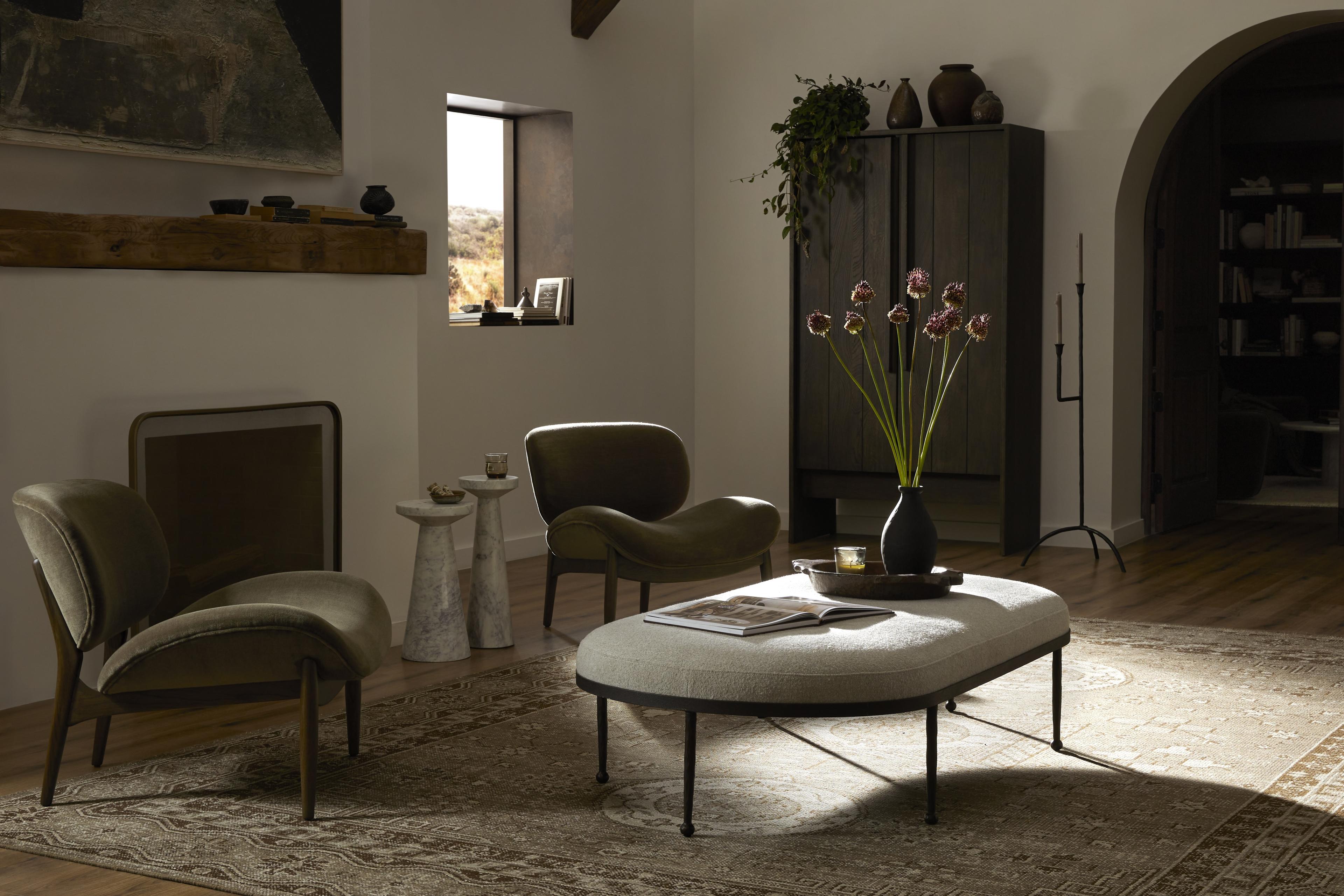 Green velvet chairs and oval upholstered coffee table in cozy sitting room.