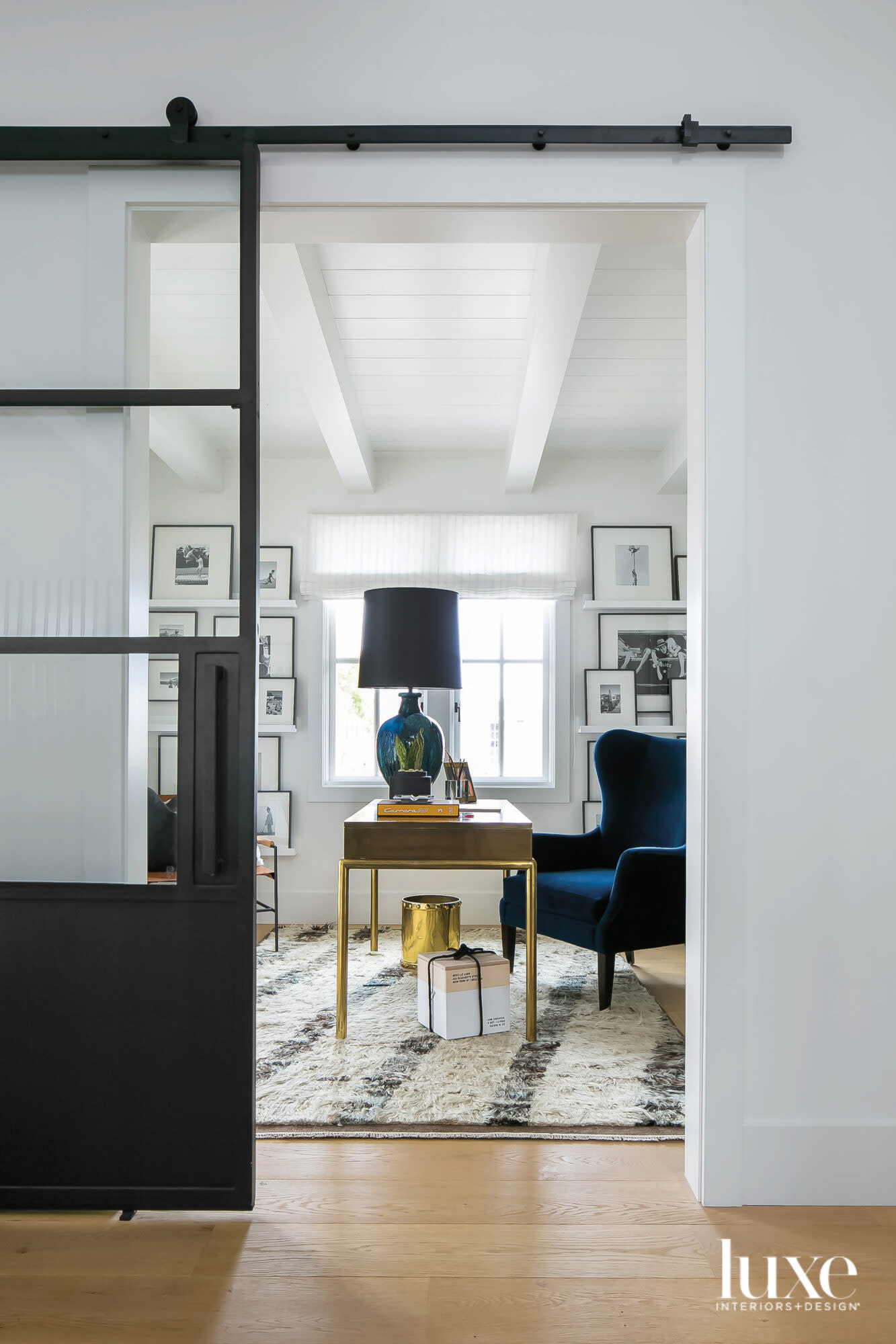 View into office with blue chair and collection of photography on the walls