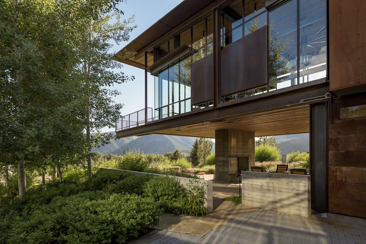 A house nestled among lush trees and towering mountains.