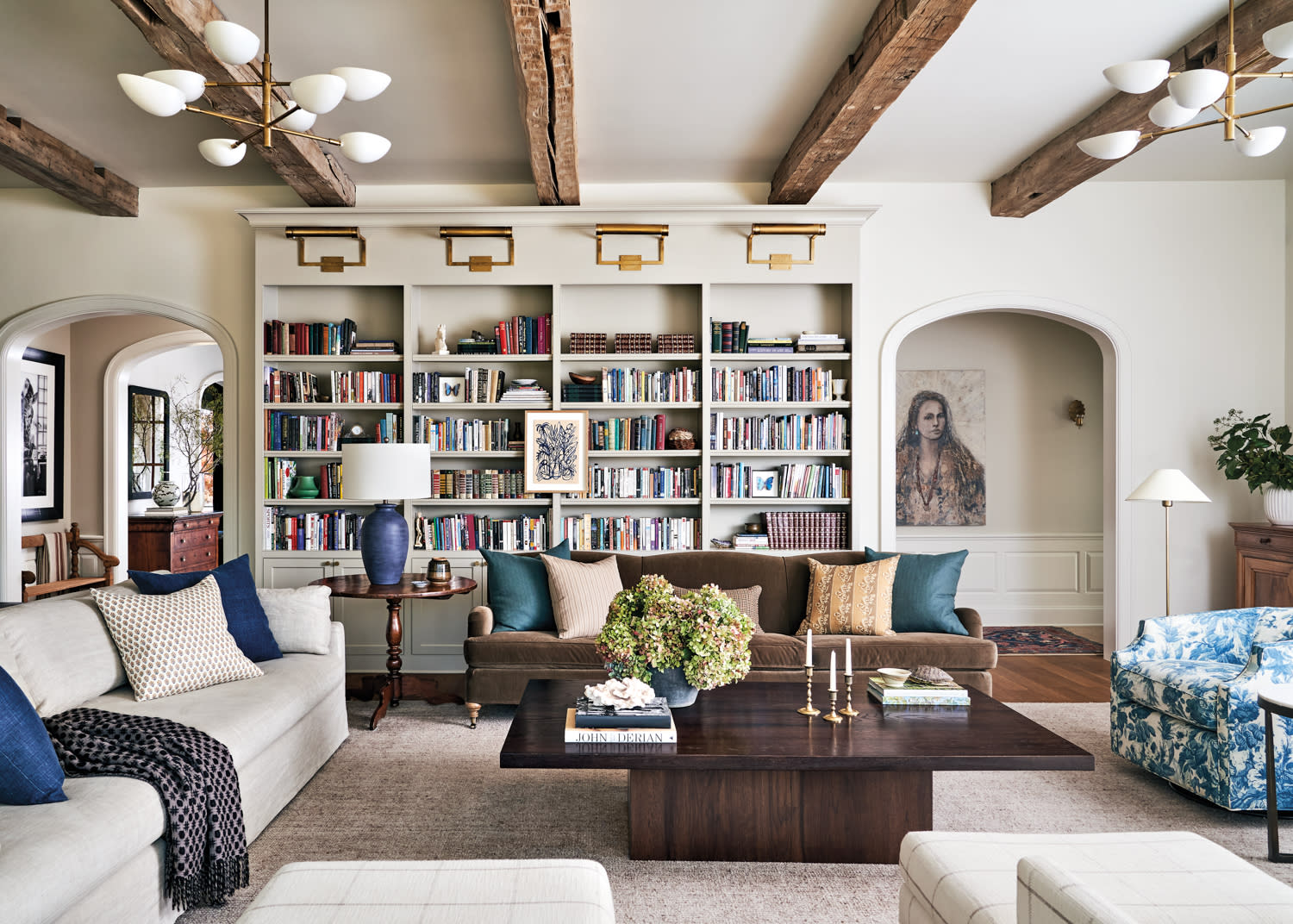 living room with exposed beams, built-in bookshelves full of books, cozy sofas and chairs