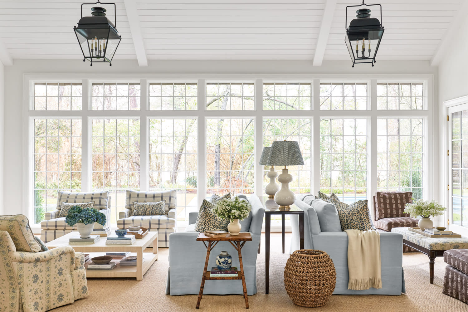 living room with two blue sofas, checkered armchairs and large windows facing the outside scenery