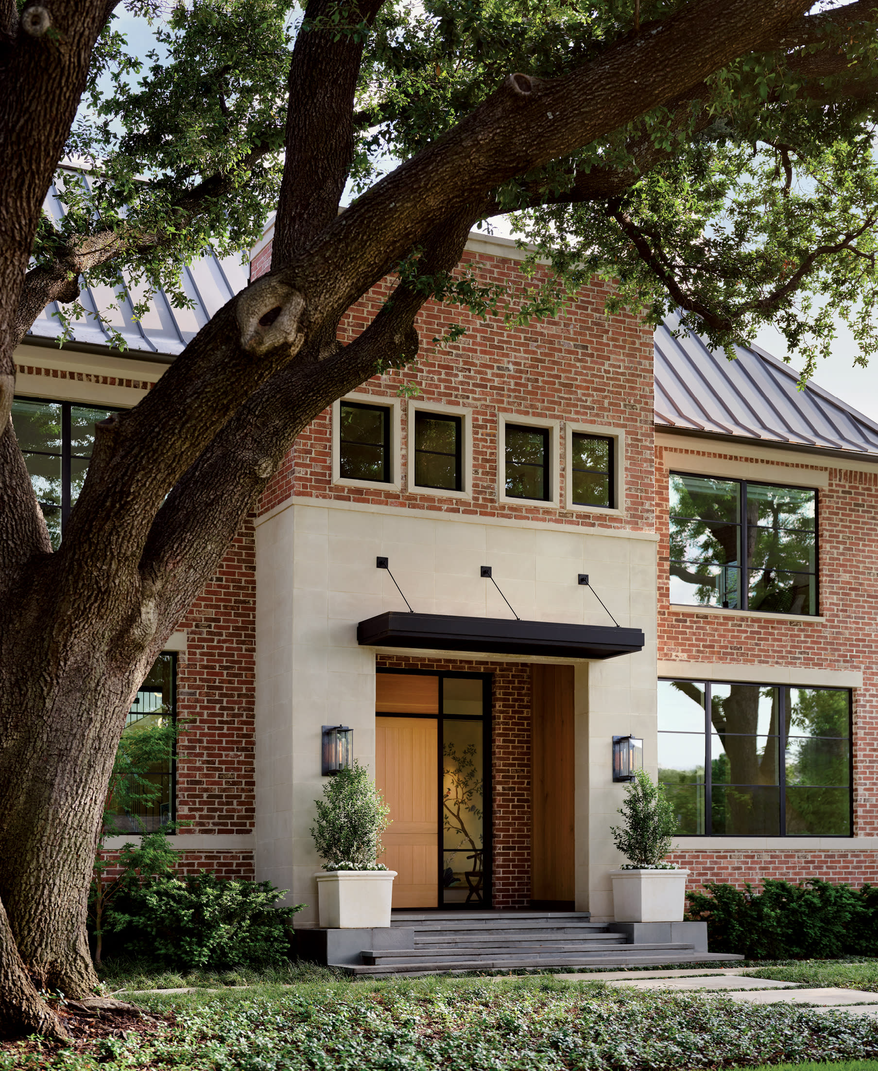 brick home exterior behind a tall bending tree