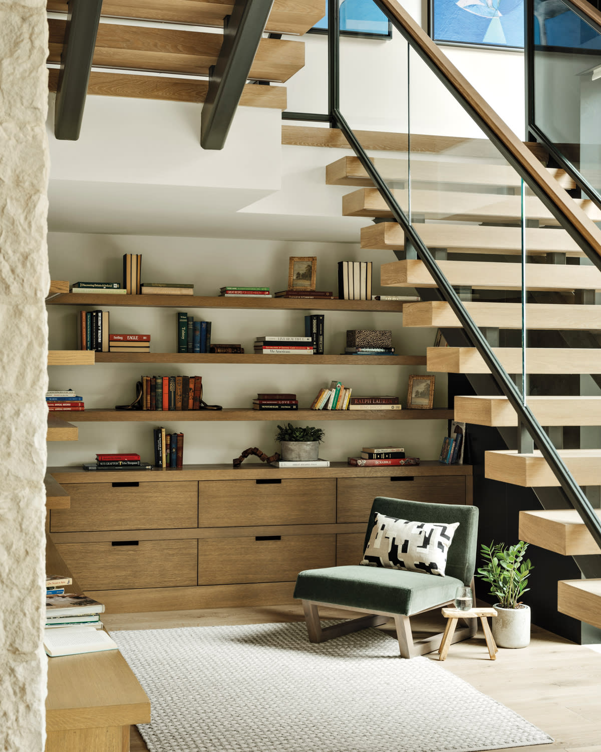 cozy reading nook beneath oak, metal and glass stairs