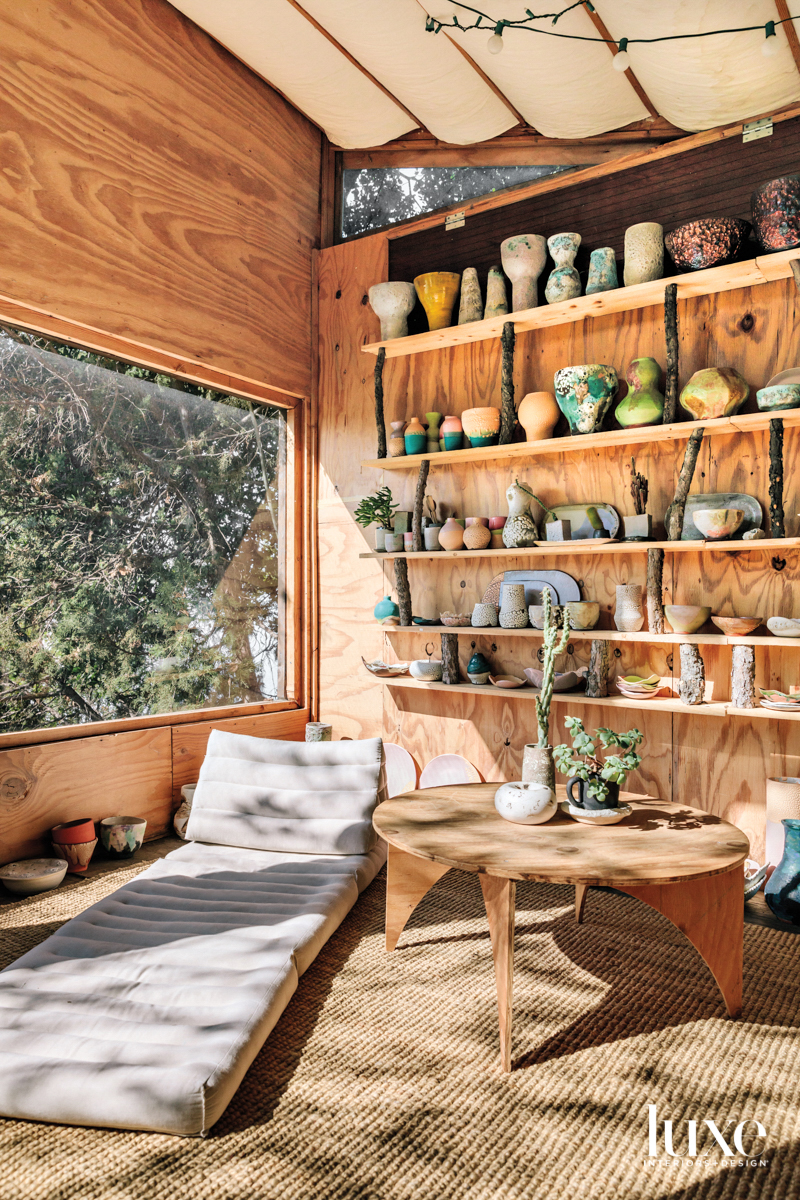 Lee's studio with a low daybed, small table and display of ceramic pieces