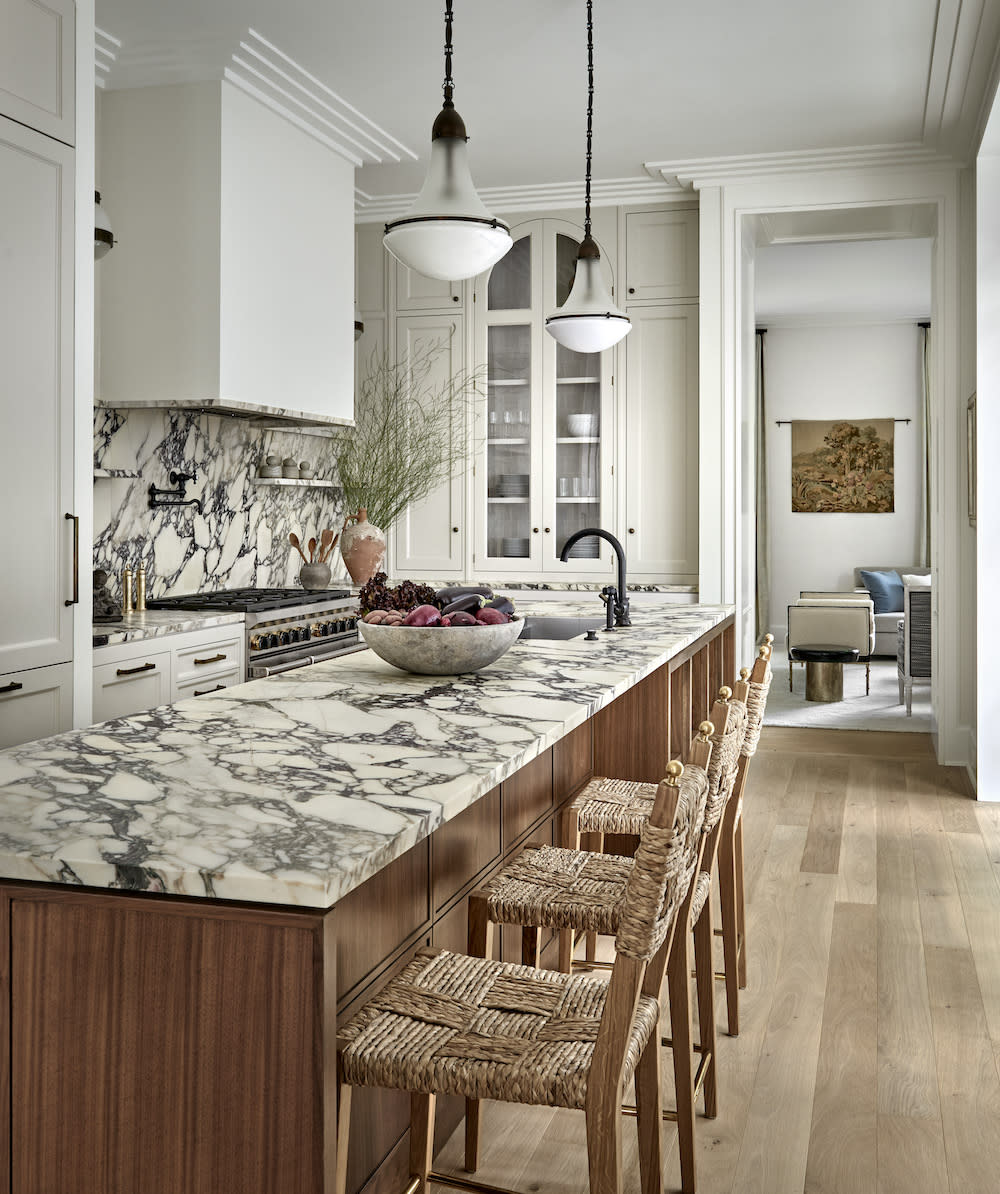 Kitchen island with marble countertops, four wicker and wood stools.