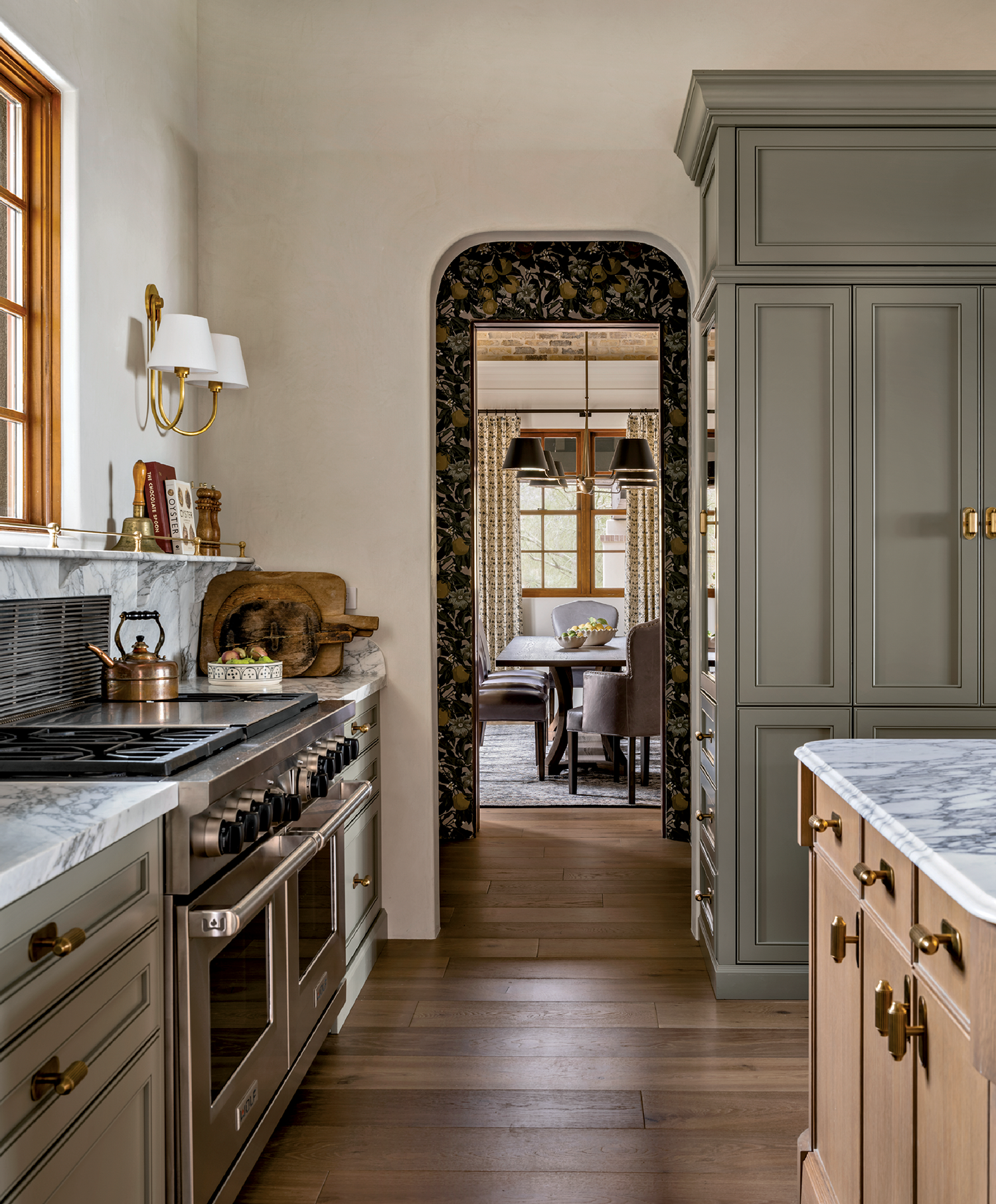 Warm-toned kitchen with marble counters, gray cabinets, and a dual oven