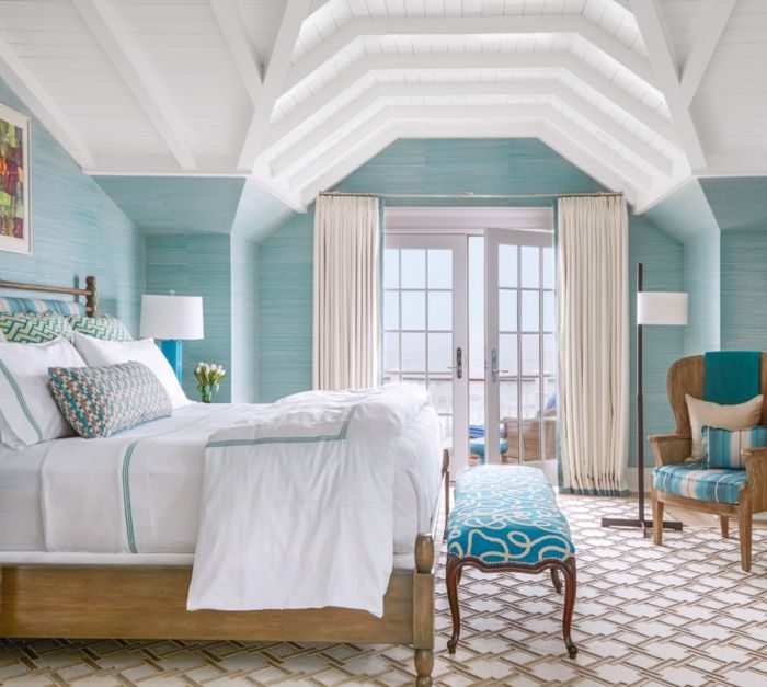In the master bedroom, nightstands by David Iatesta flank the bed, which is dressed in custom white linens with turquoise and tan details by Cristina Azario. The turquoise stripe on the barrel chair is from Osborne & Little, and the breezy woven draperies are made of Rumba fabric from Romo, trimmed in seafoam slub tape from Lee Jofa.