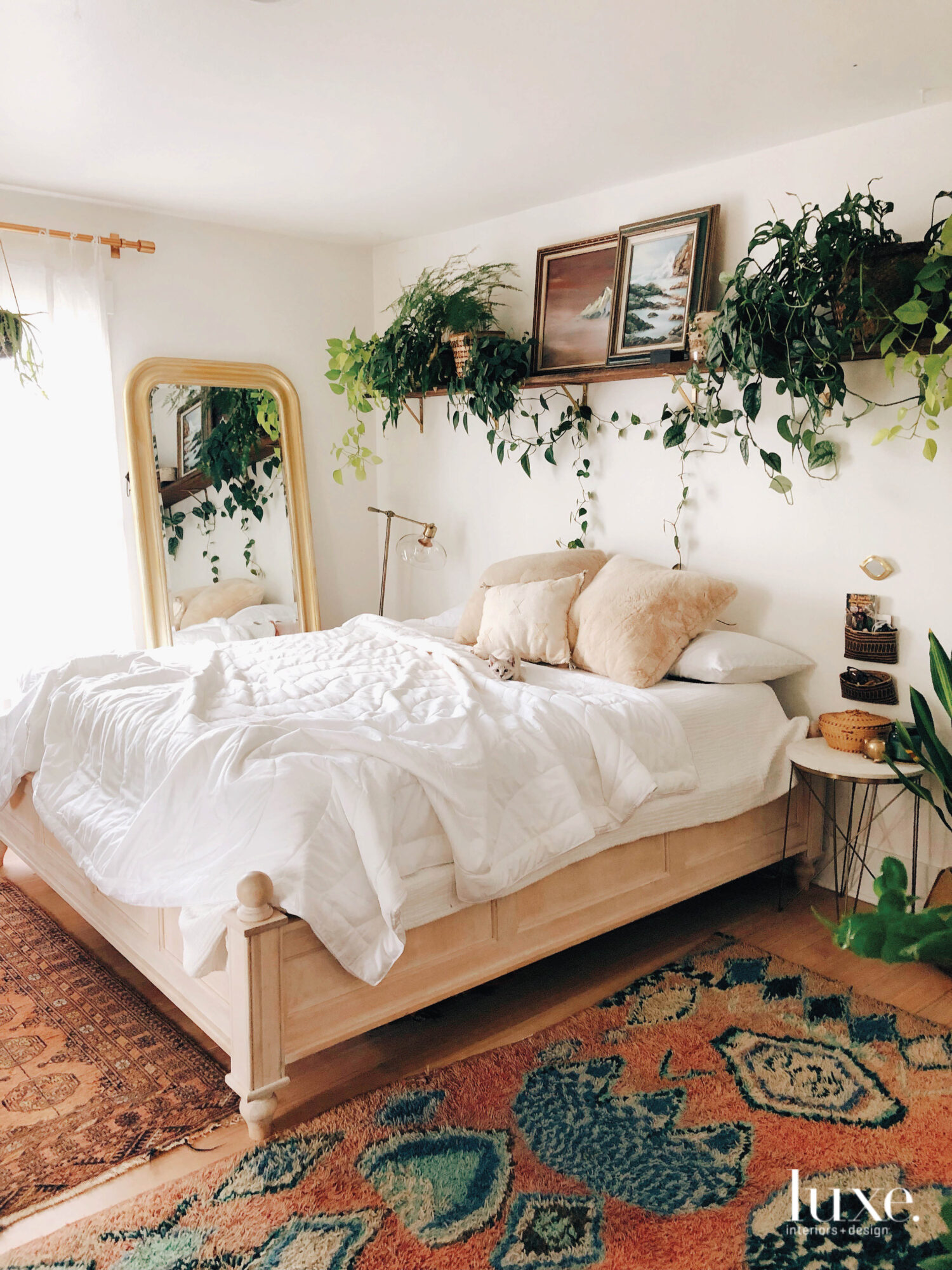 A peach and white colored bedspread is framed with dark green plants all over