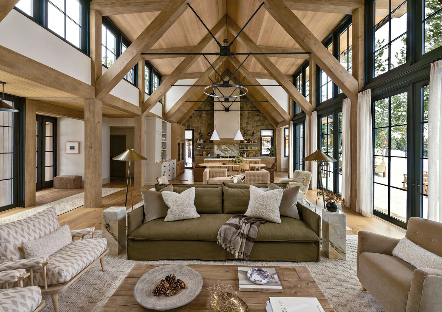 Spacious living room with high vaulted ceiling, exposed wooden beams, and large windows.