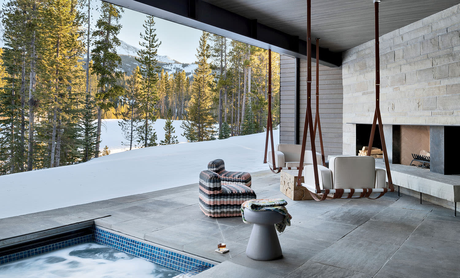 cozy spa terrace featuring a hot tub and a fireplace, overlooking views of snowy mountains
