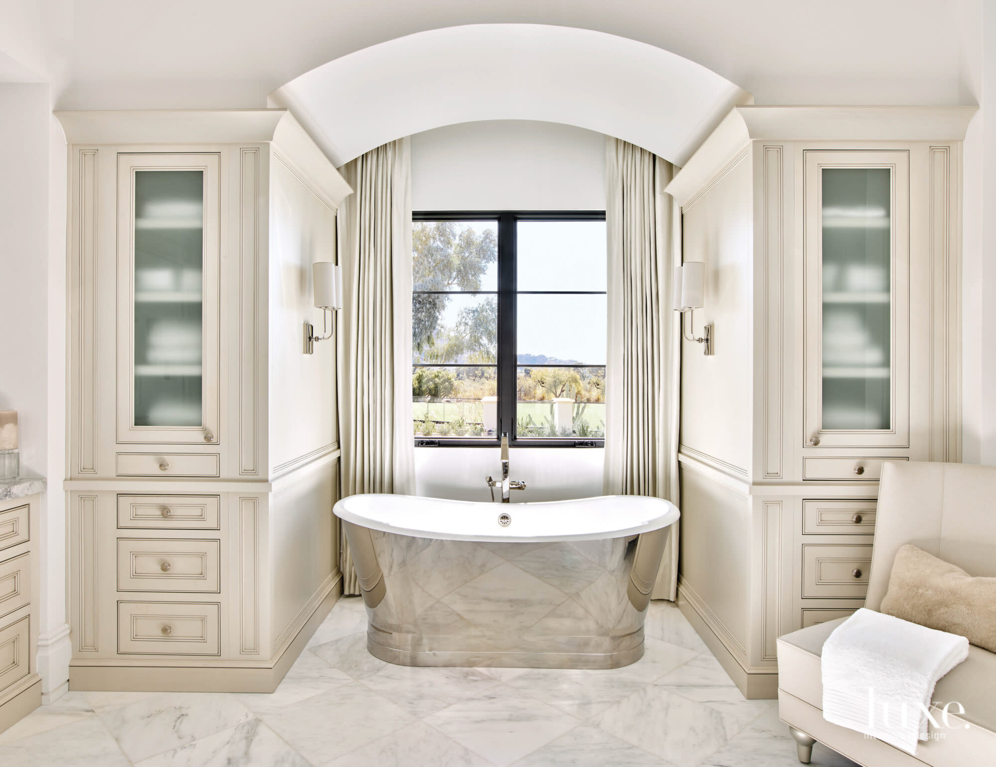 A mirrored tub sits in front of the window in the clients' bathroom.