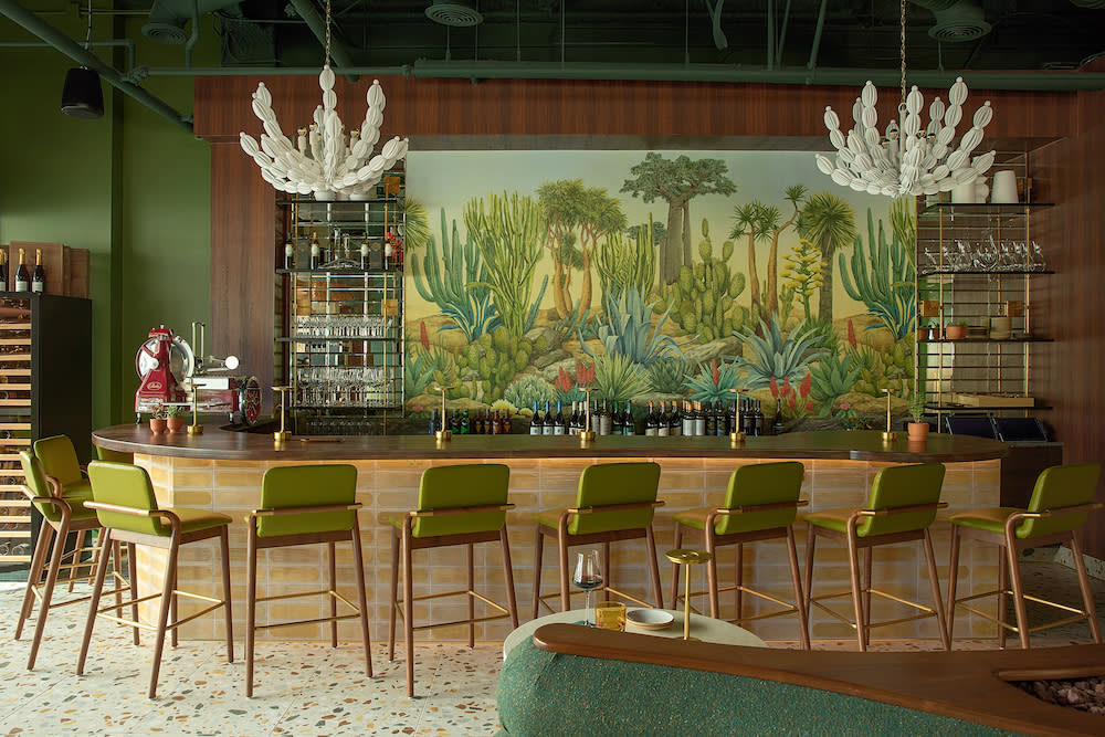 custom mural behind a mid-century modern bar with green stools.