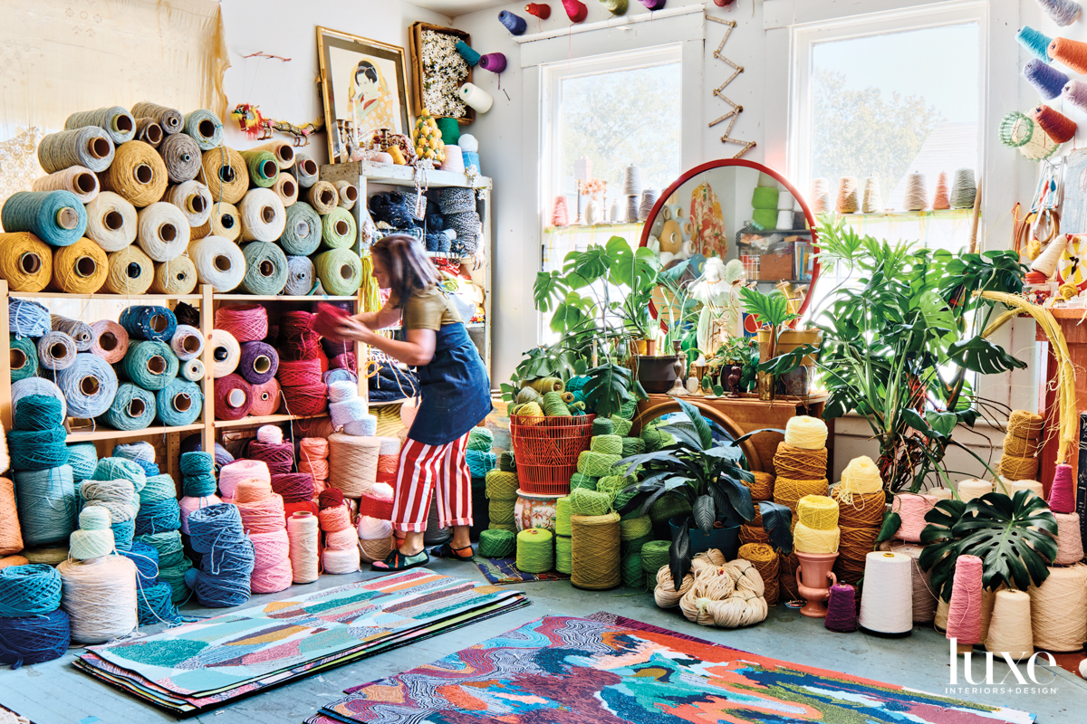 Spacious artist studio filled with colorful floor mats and shelves stacked with colorful spools of yarn