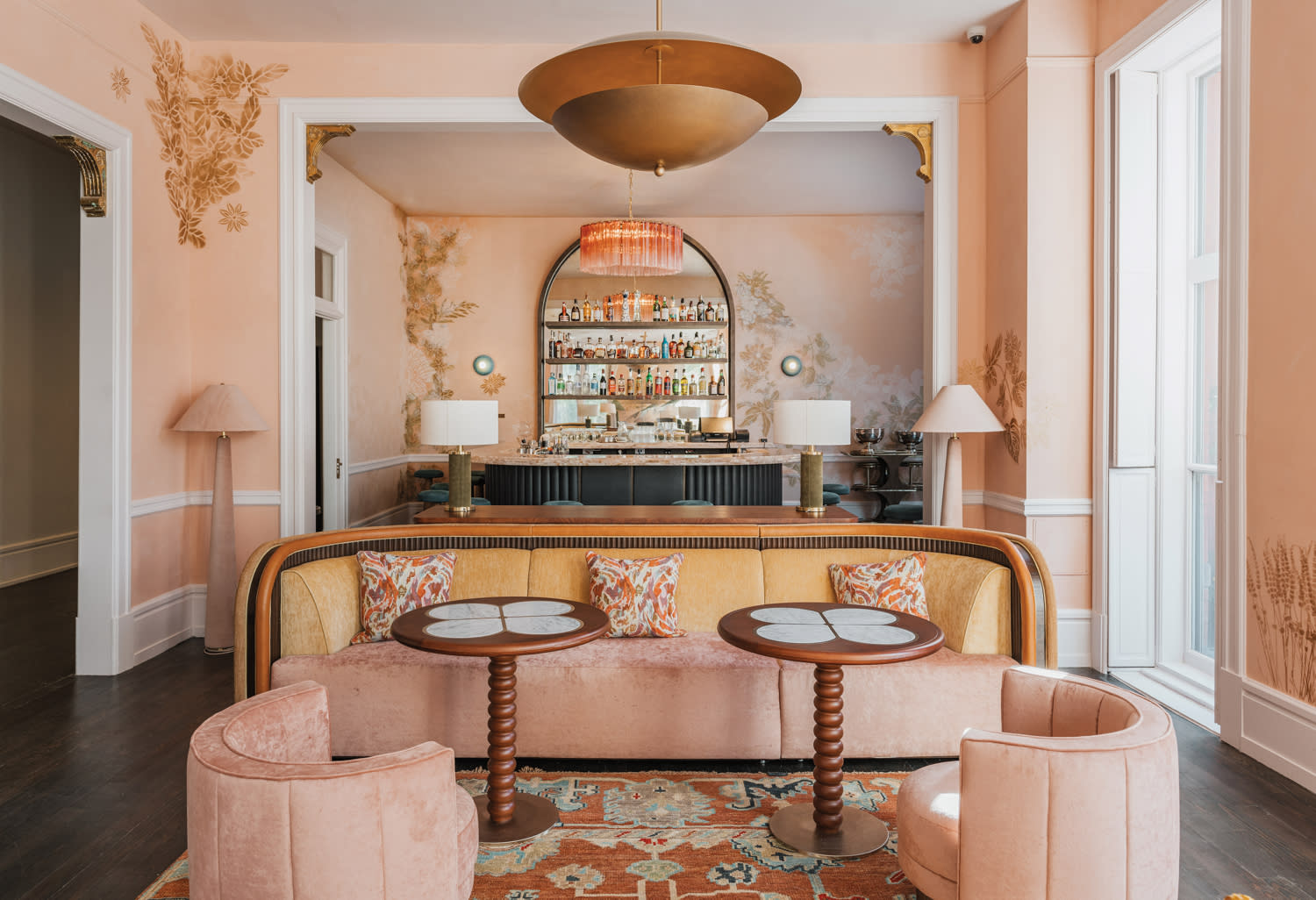 lounge with a blush-pink palette, velvet banquette, swivel chairs and mirrored-backed bar