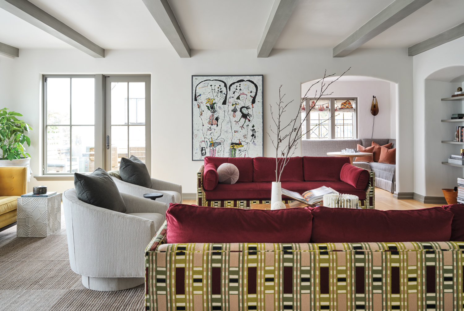 living area with colorful red sofas and patterned backing alongside grey armchairs