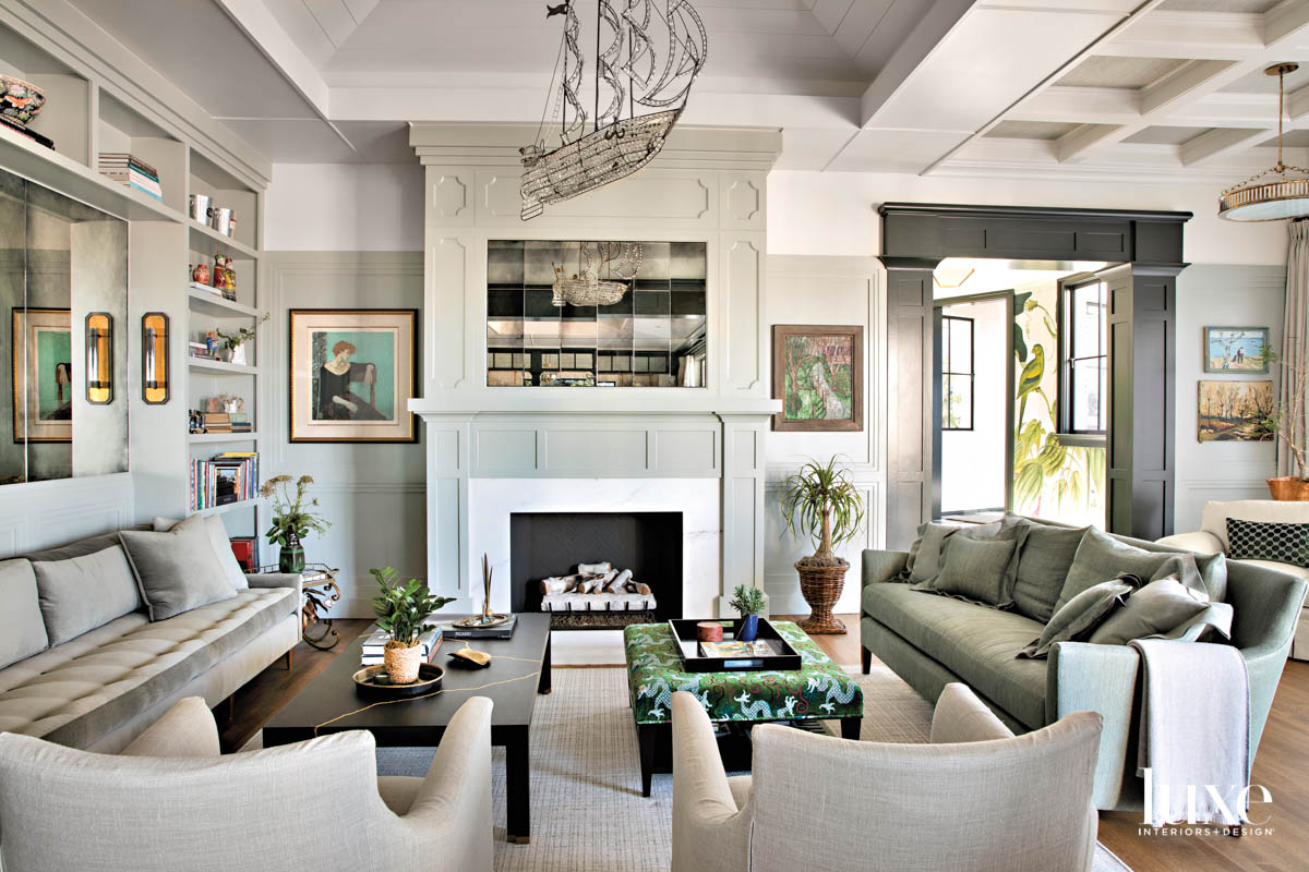 View of living room facing fireplace. Two couches and pair of lounge chairs. Ship form chandelier above.