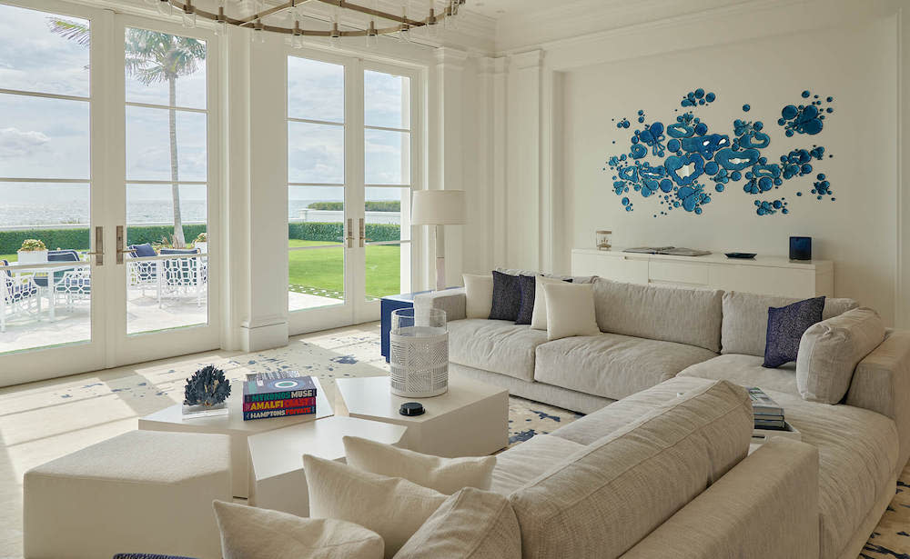 A bright living room featuring elegant white furniture adorned with vibrant blue flowers, creating a serene atmosphere.