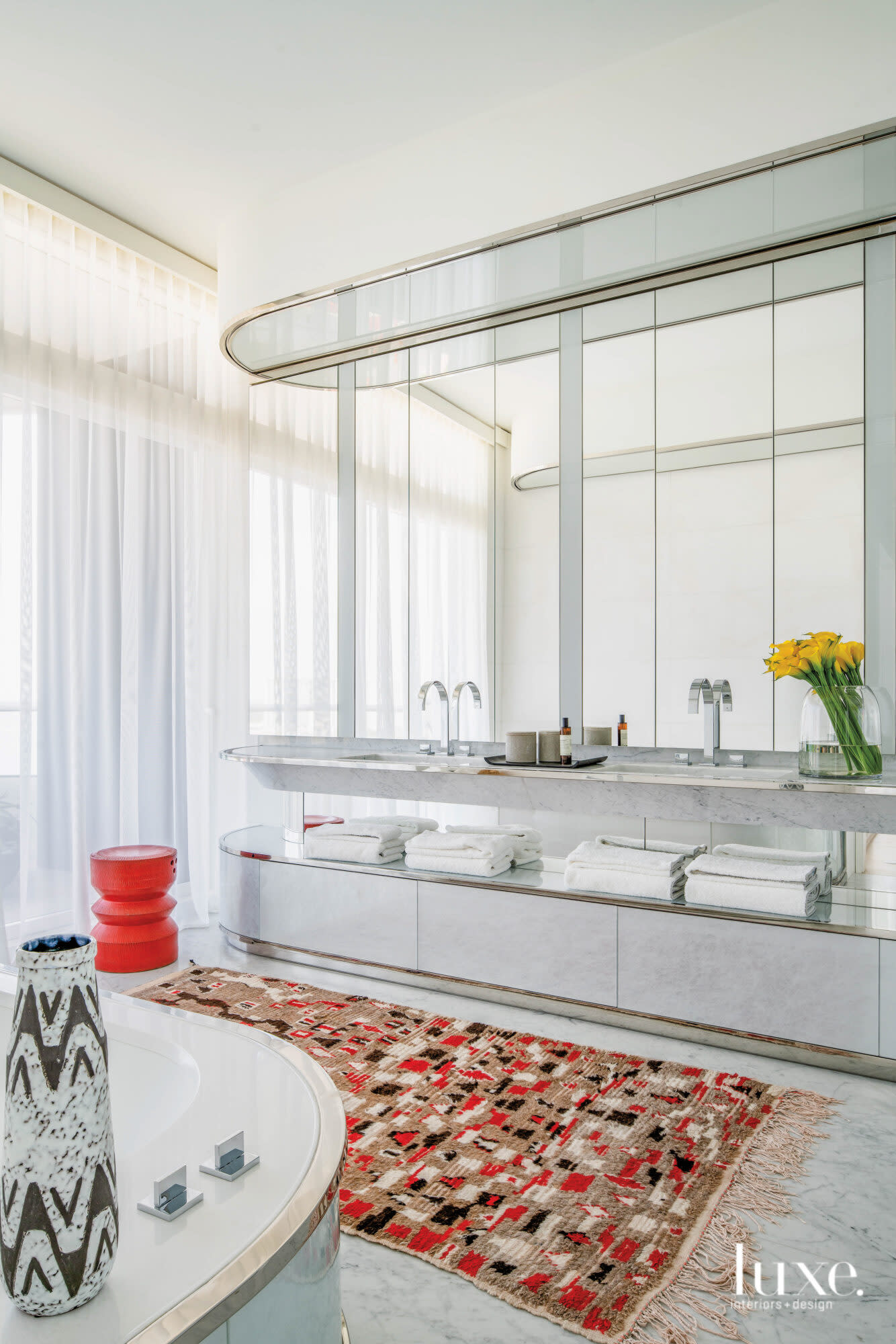 Master bathroom with bold red stool and vintage Moroccan rug