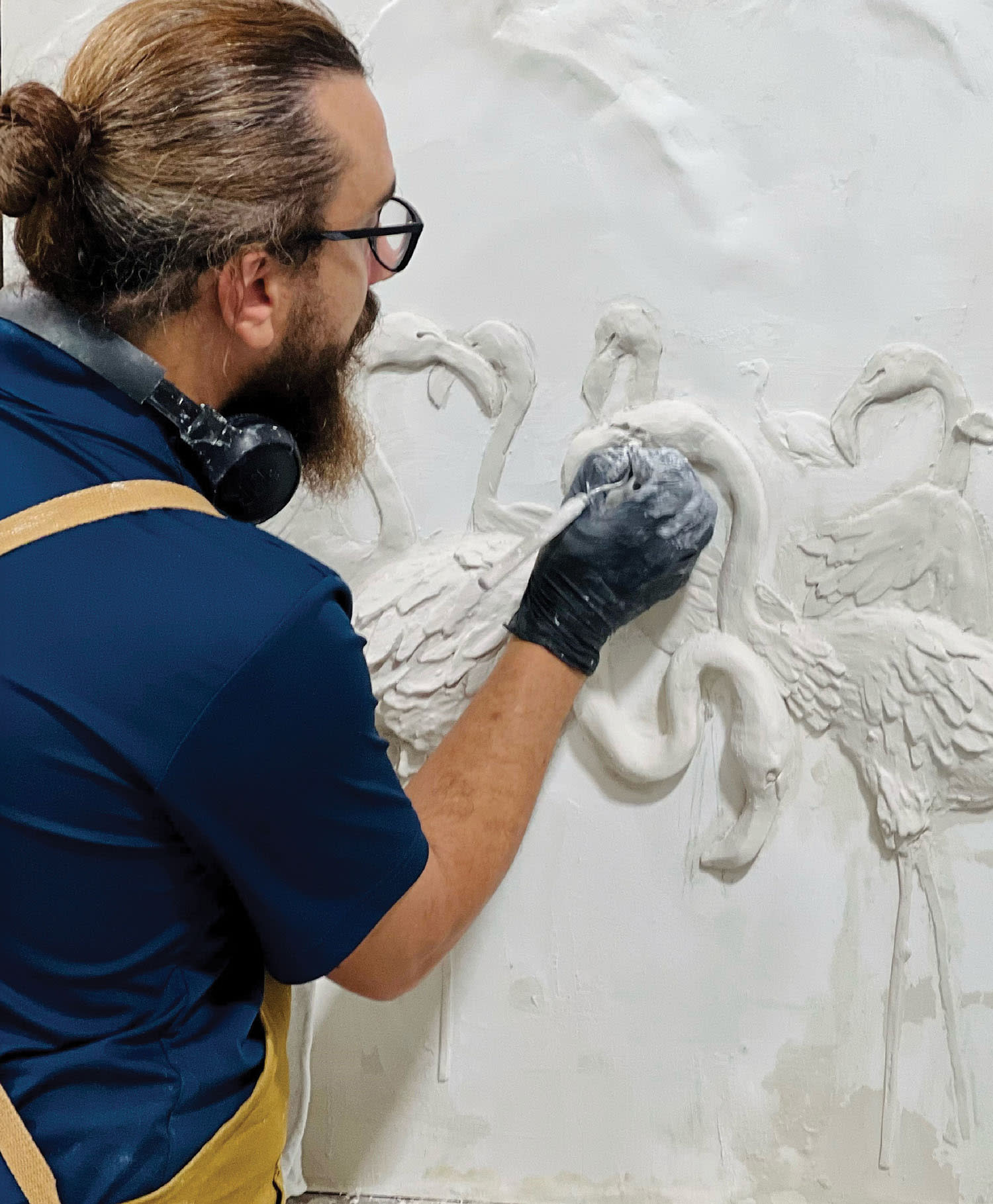 a sculptor works on a flamingo relief