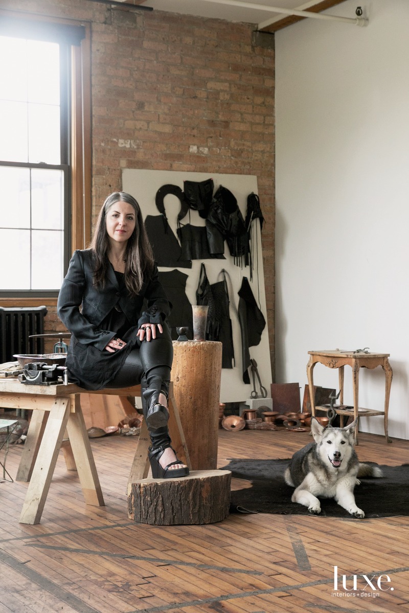 Prieto-Velasco sits with her Siberian Husky, Quinn, in her studio, which is filled with various hammers and bowls.