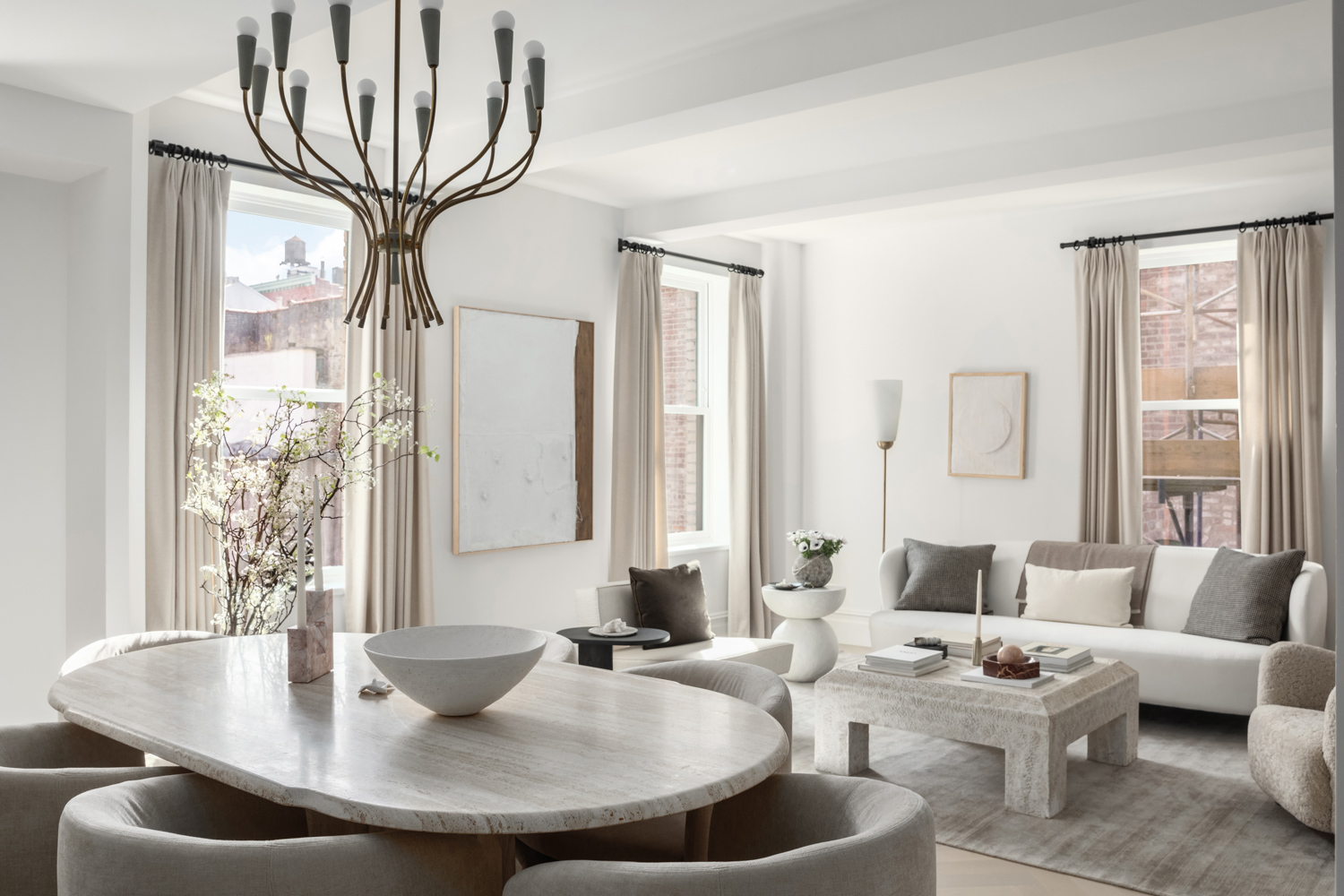 Gray and white dining room and living area with a brass chandelier