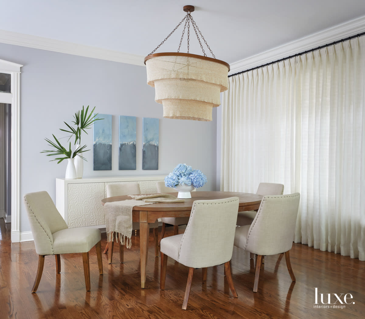 dining room with floor to ceiling drapery, round table and cloth covered chairs