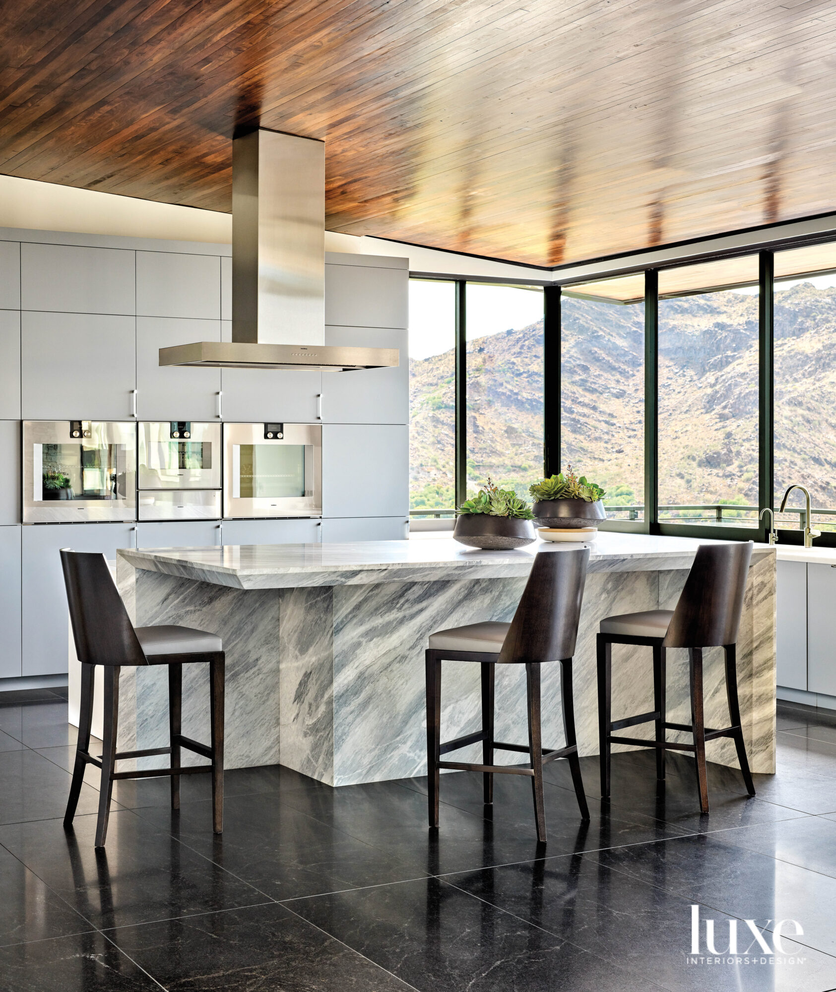 A modern kitchen with built-in appliances and a large marble island.