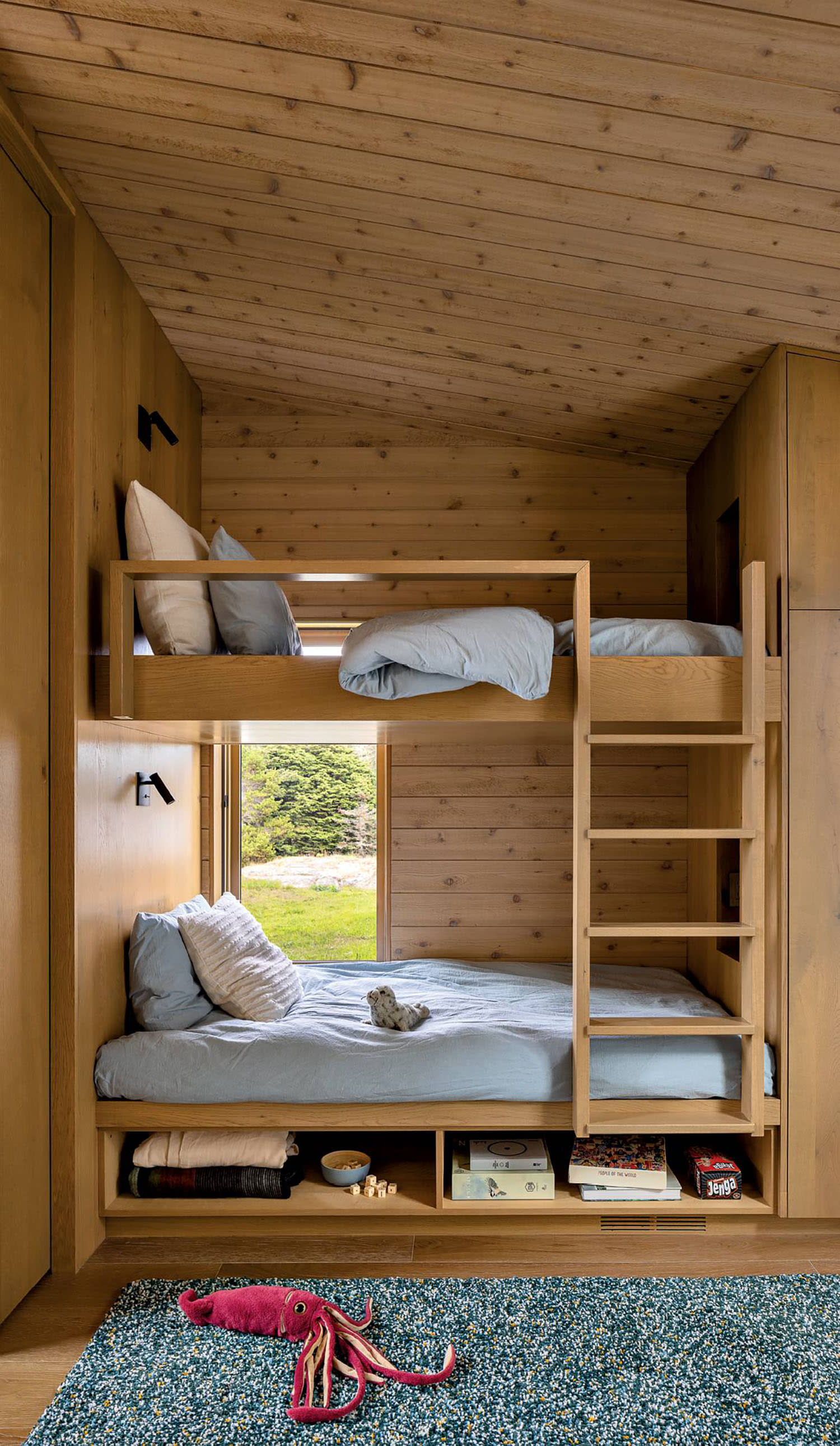 A set of wood bunk beds with a ladder, made up with blue and white linens, and shelves underneath.
