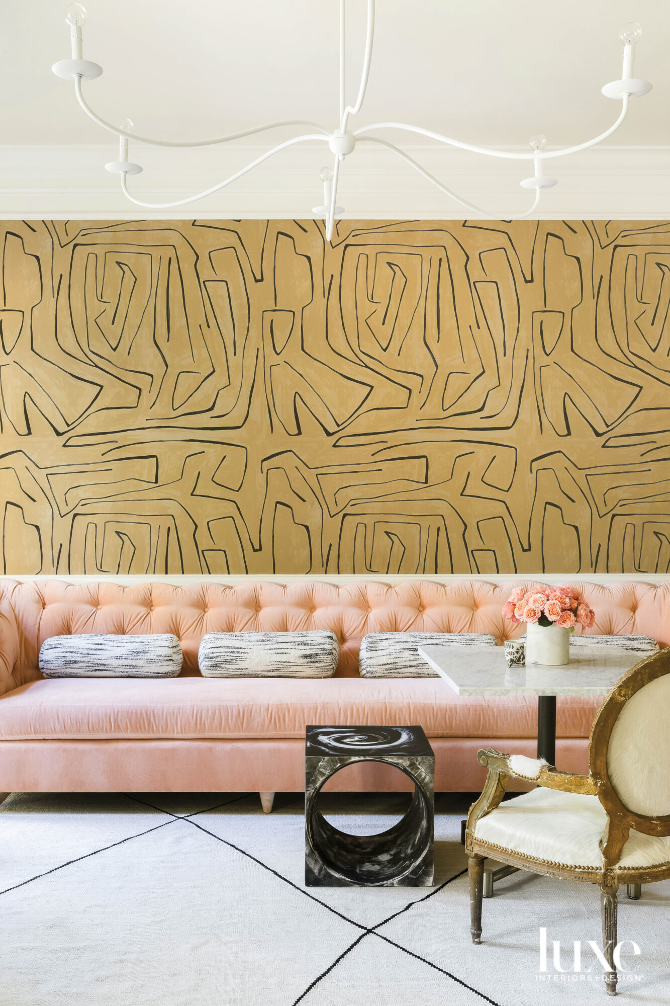 Tufted peach velvet banquette with funky wallpaper and bistro table