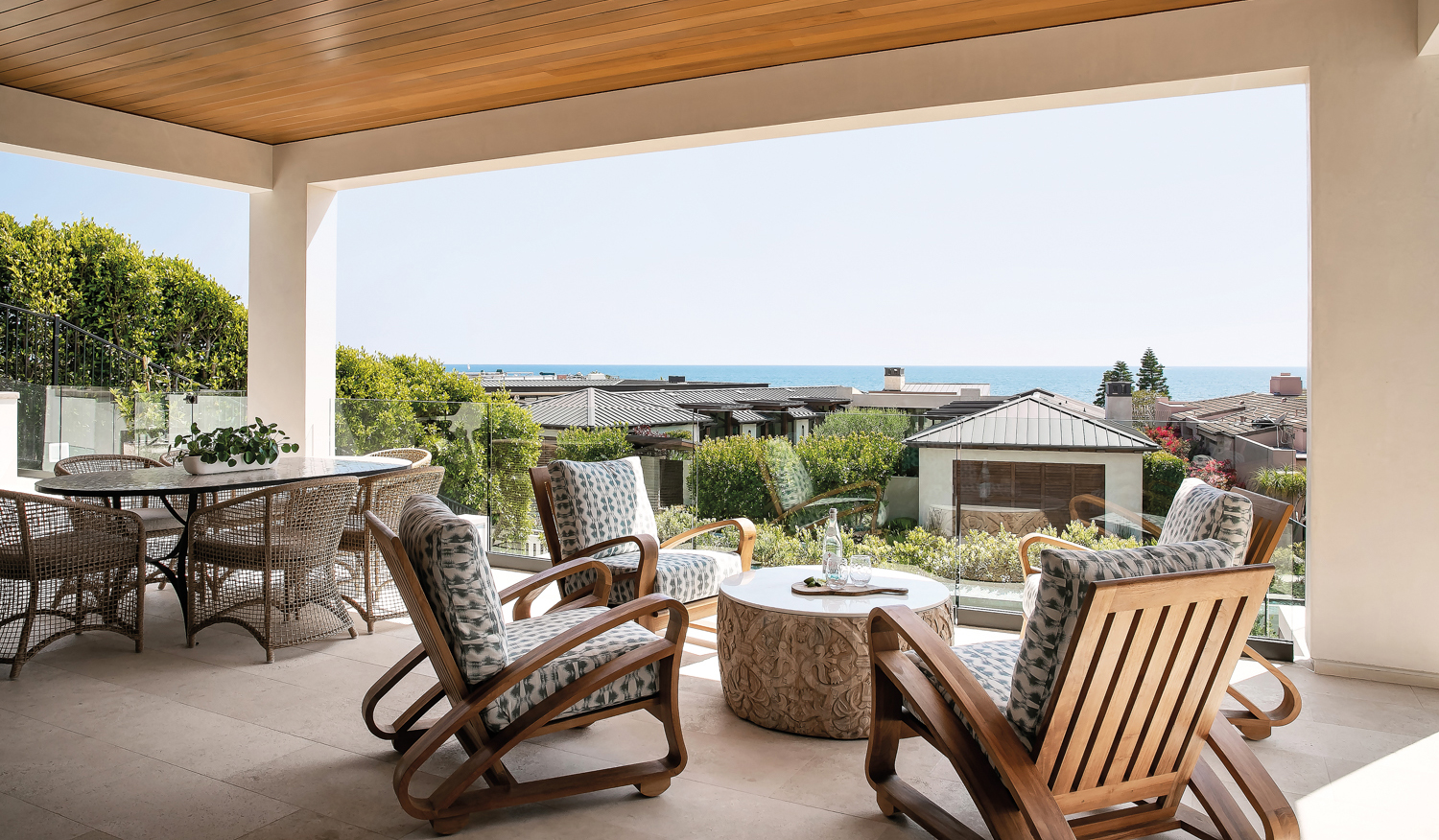 outdoor covered dining and lounge patio with chairs surrounding a found carved wood table