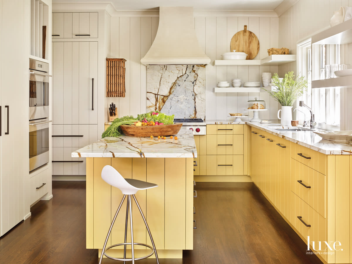 sunny kitchen with yellow cabinets and dramatically veined marble