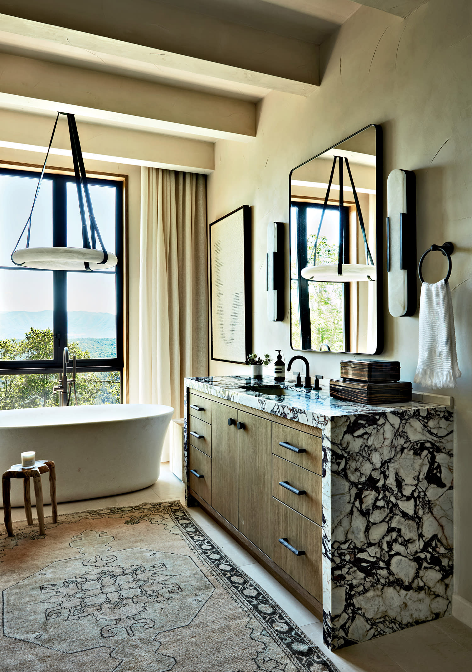 A modern luxurious bathroom with a bathtub next to a window, a vanity sink, and mirrors hanging on the walls.