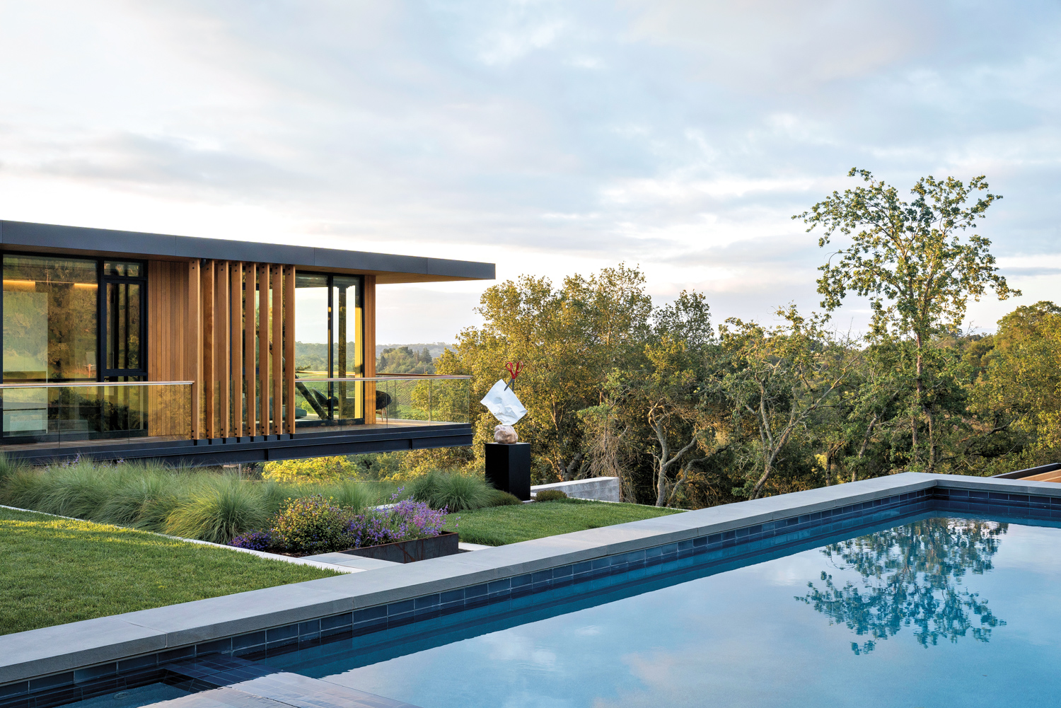 A house is perched on a hill and above a pool.