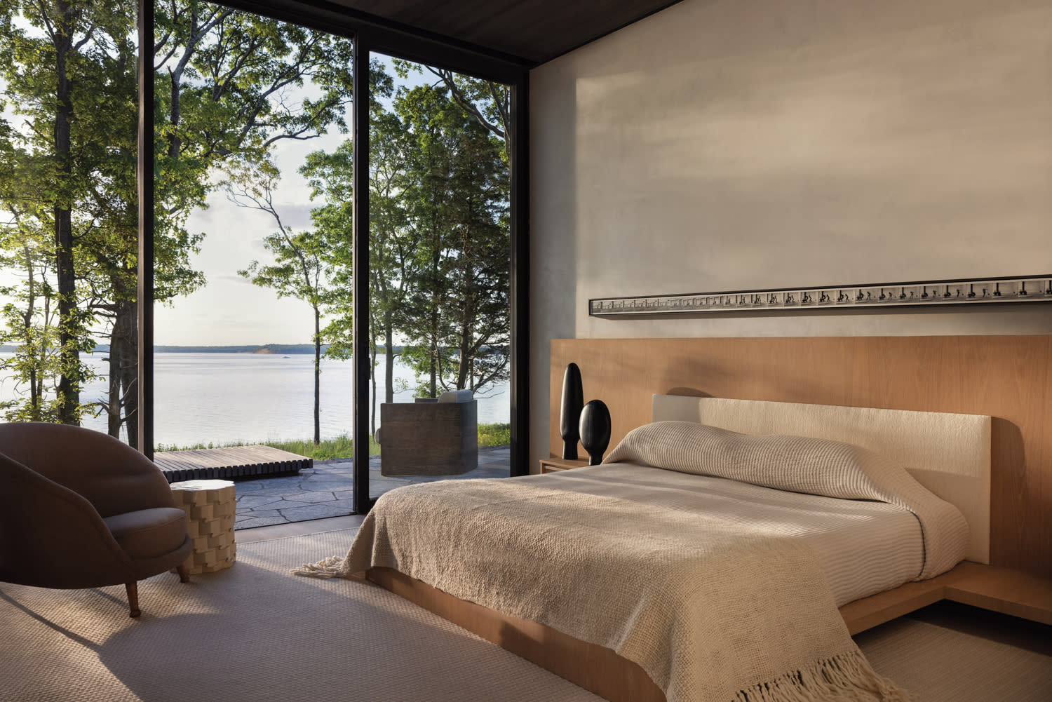 calm, neutral bedroom with a custom oak headboard and views of Sag Harbor